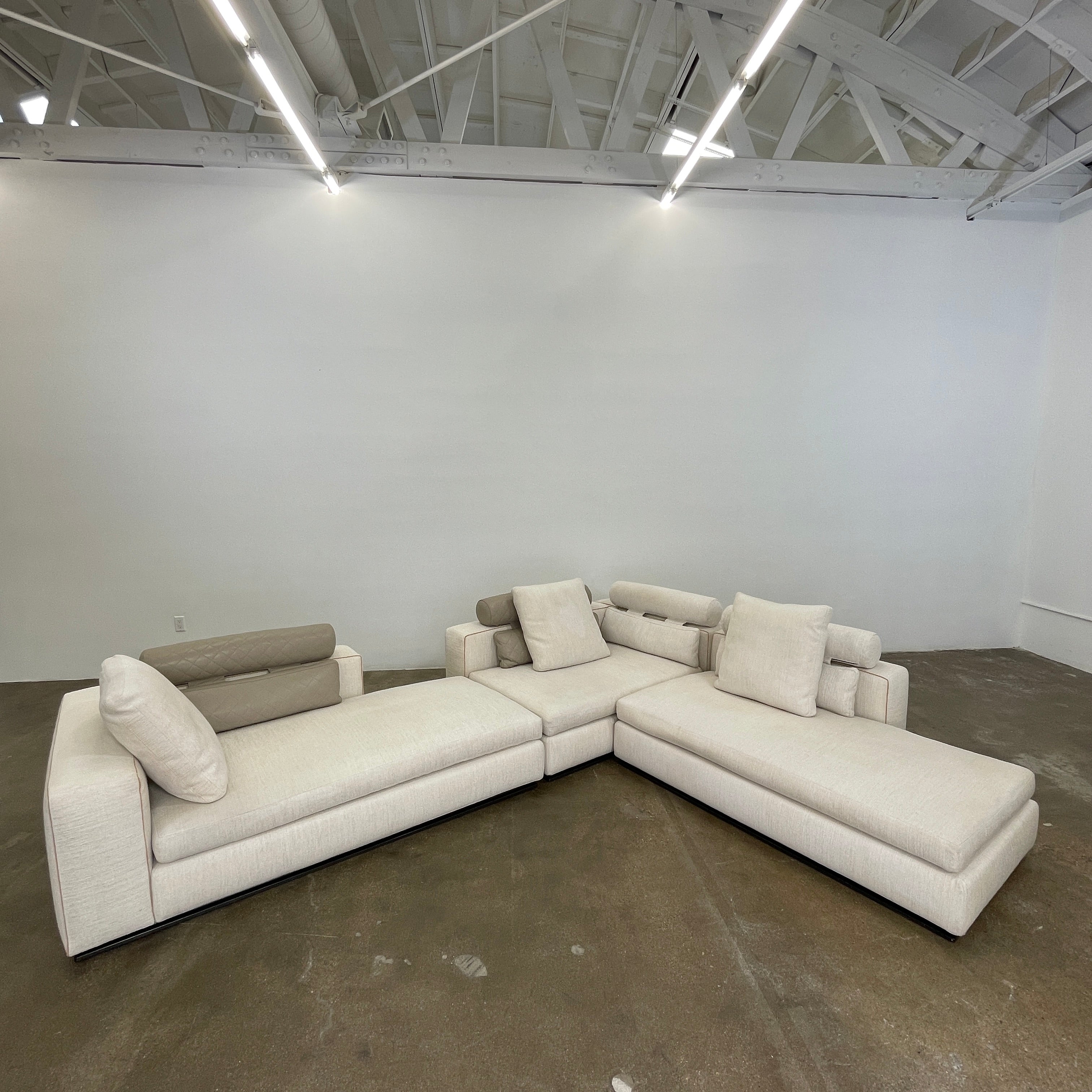 The Minotti Leonard 3 Piece Sectional by Minotti features an L-shaped beige design with three seat sections, multiple back and side cushions, and a right-side chaise lounge—ideal for an elegant living space—shown on a plain white background.