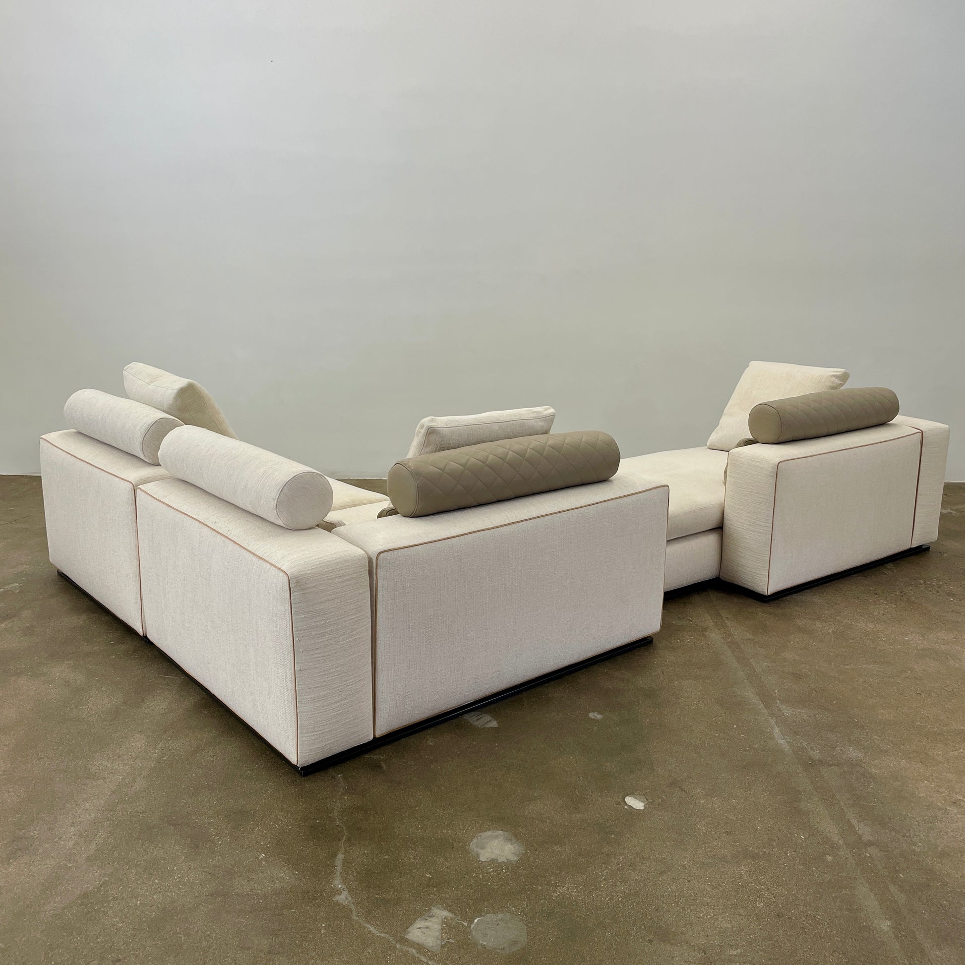 The Minotti Leonard 3 Piece Sectional by Minotti features an L-shaped beige design with three seat sections, multiple back and side cushions, and a right-side chaise lounge—ideal for an elegant living space—shown on a plain white background.