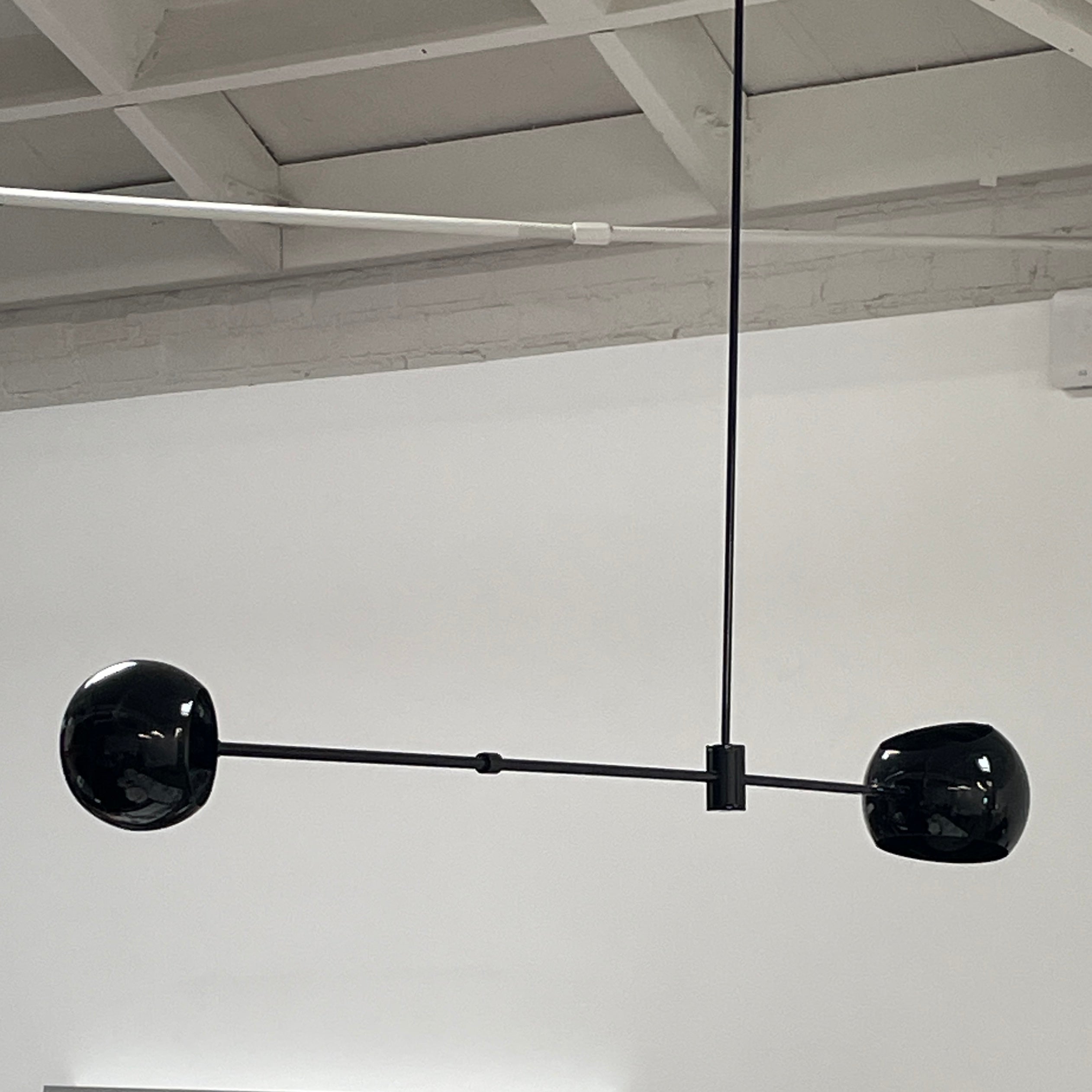 The David Weeks Studio Abaca Suspension Light is a custom-made, black, modern hanging fixture with two spherical bulbs. Crafted from powder-coated steel, it elegantly suspends from ceilings with exposed beams to add sophistication to any space.