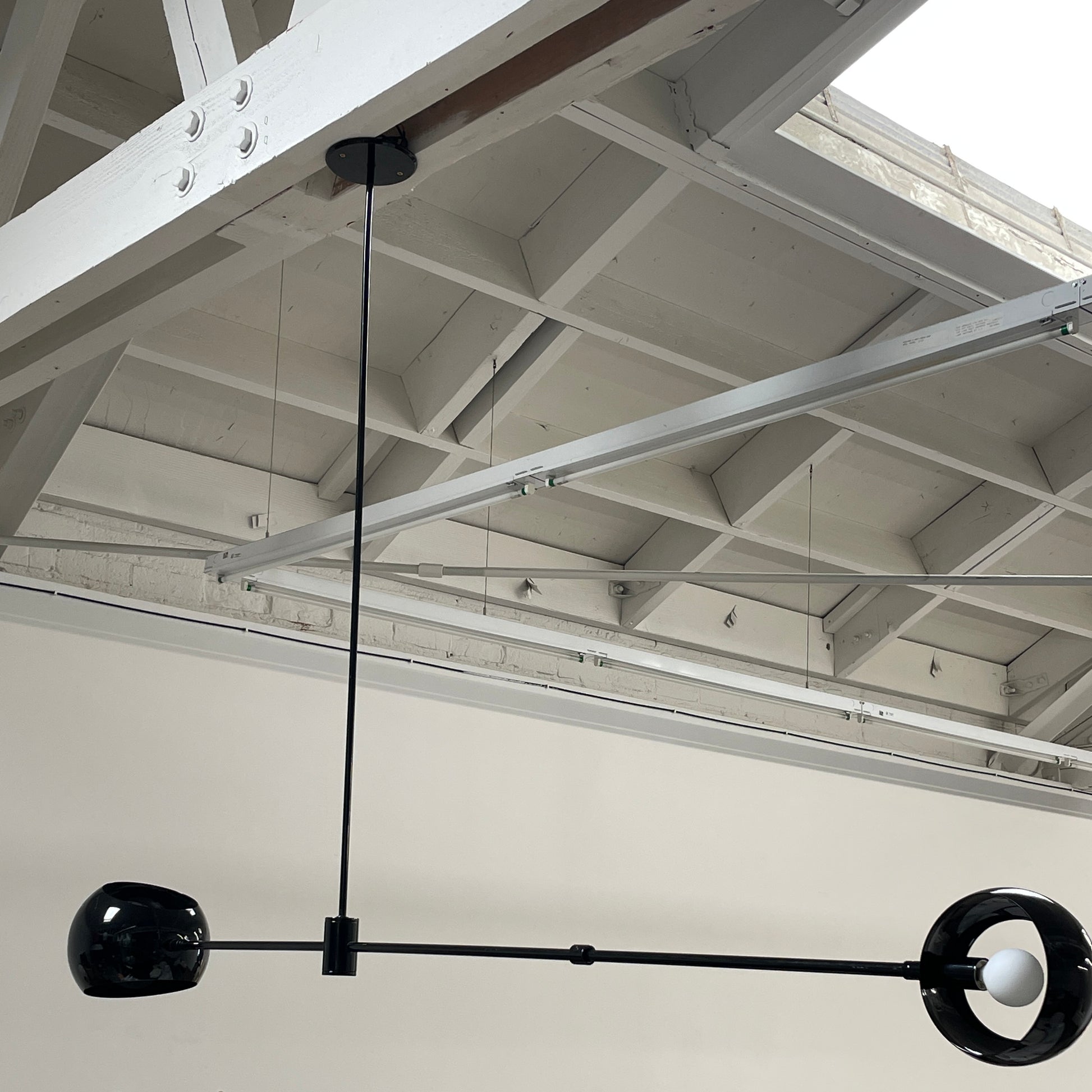 The David Weeks Studio Abaca Suspension Light is a custom-made, black, modern hanging fixture with two spherical bulbs. Crafted from powder-coated steel, it elegantly suspends from ceilings with exposed beams to add sophistication to any space.