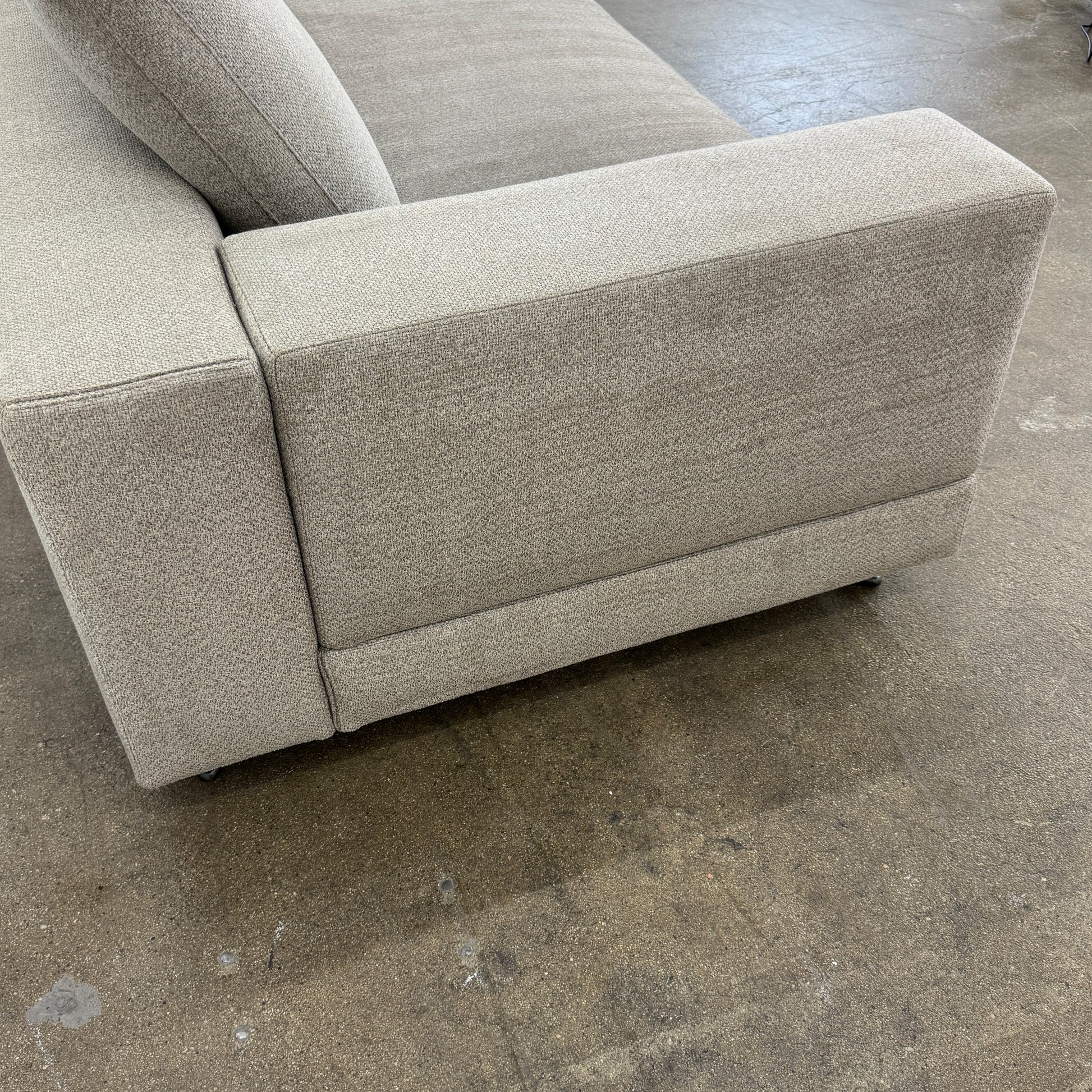 The Minotti White Sofa with Table is a beige three-seater luxury sofa featuring chenille upholstery, wide armrests, three back cushions, and an attached white side table on the right, set against a plain white wall on a brown floor.