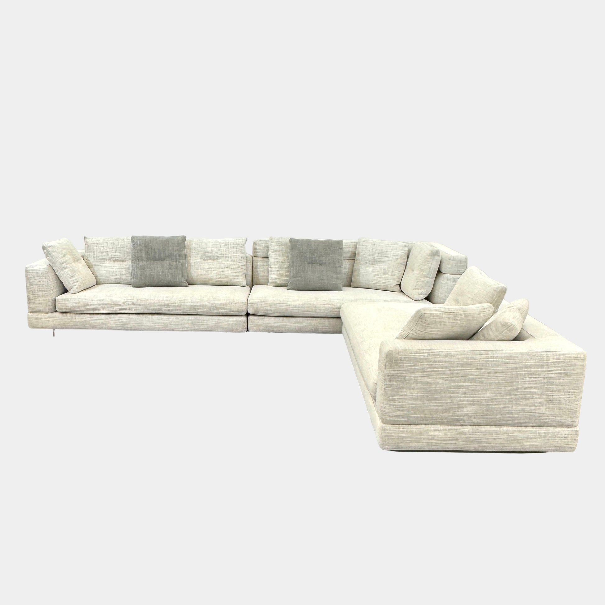 The Minotti Alexander 3 Piece Sectional by Minotti features an L-shaped design in light beige linen blend upholstery with multiple gray and beige throw pillows, set against a plain white background.