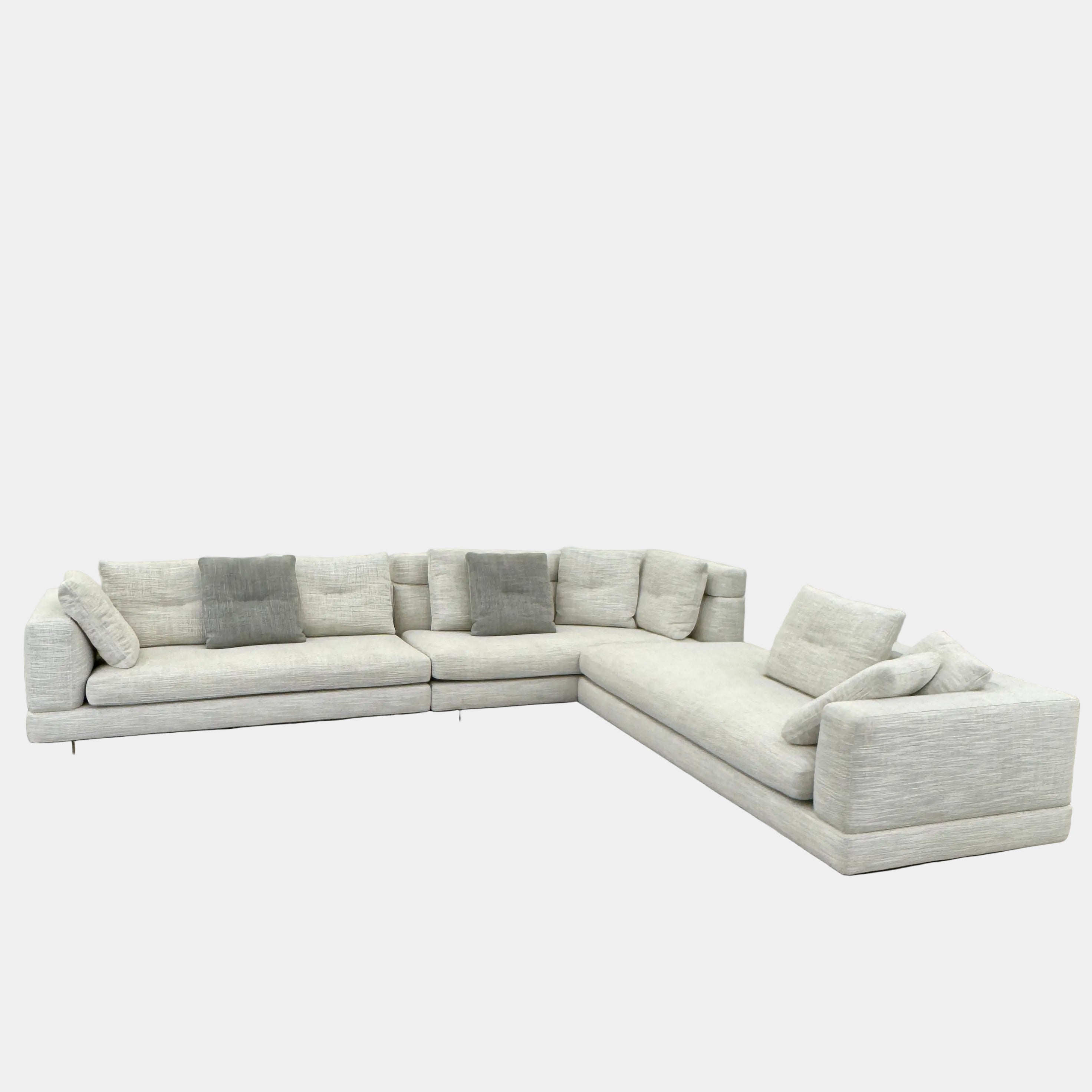 The Minotti Alexander 3 Piece Sectional by Minotti features an L-shaped design in light beige linen blend upholstery with multiple gray and beige throw pillows, set against a plain white background.