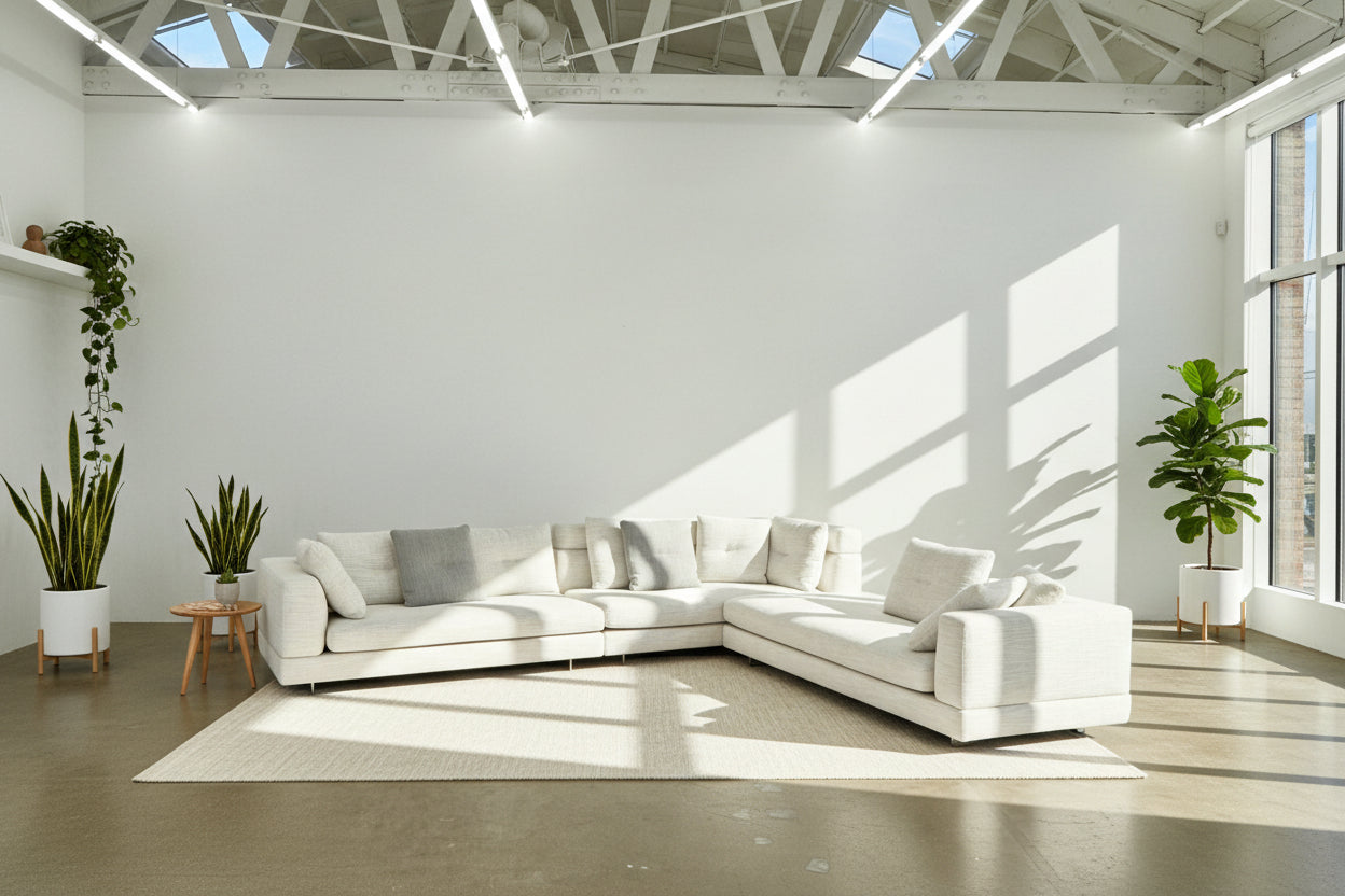 The Minotti Alexander 3 Piece Sectional by Minotti features an L-shaped design in light beige linen blend upholstery with multiple gray and beige throw pillows, set against a plain white background.