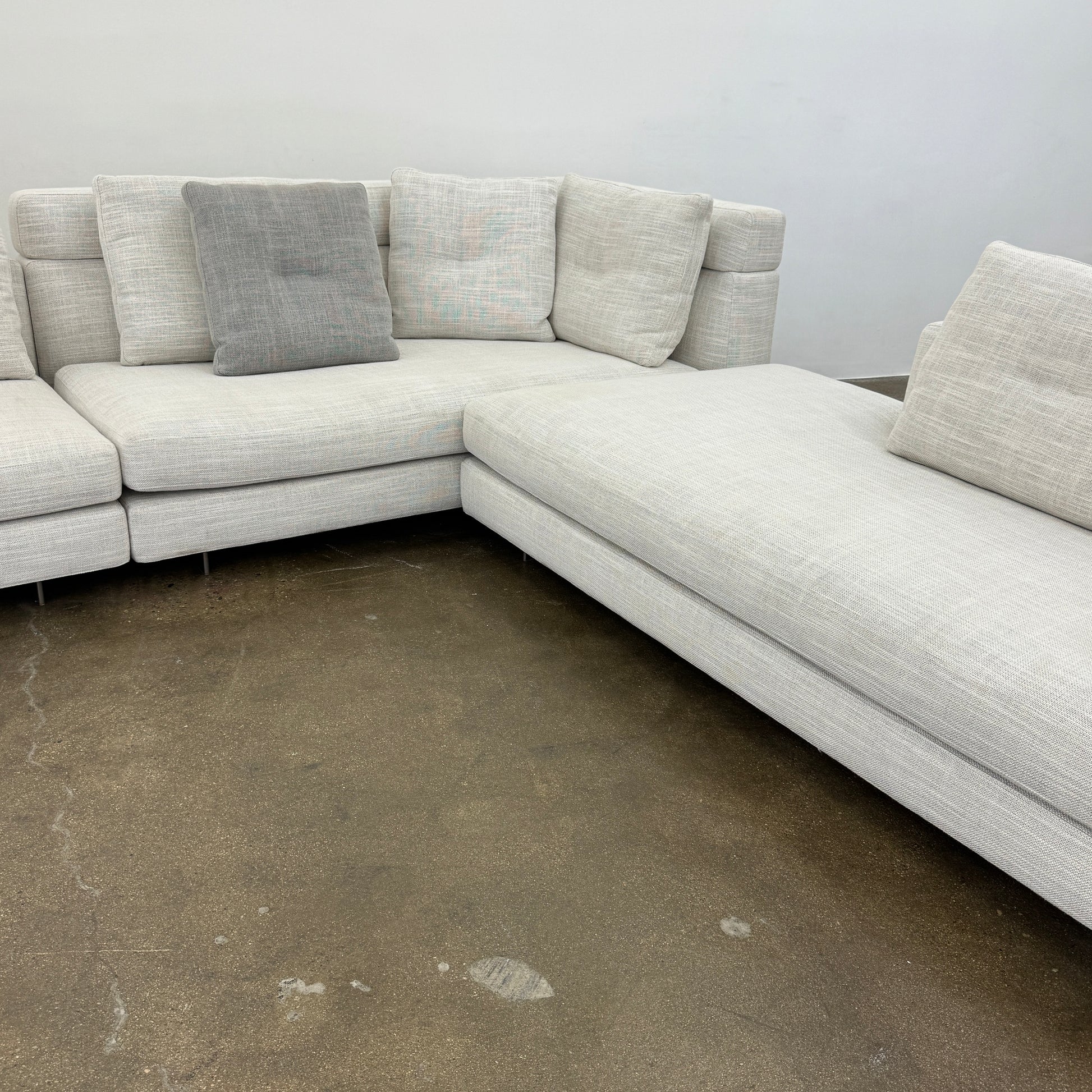 The Minotti Alexander 3 Piece Sectional by Minotti features an L-shaped design in light beige linen blend upholstery with multiple gray and beige throw pillows, set against a plain white background.