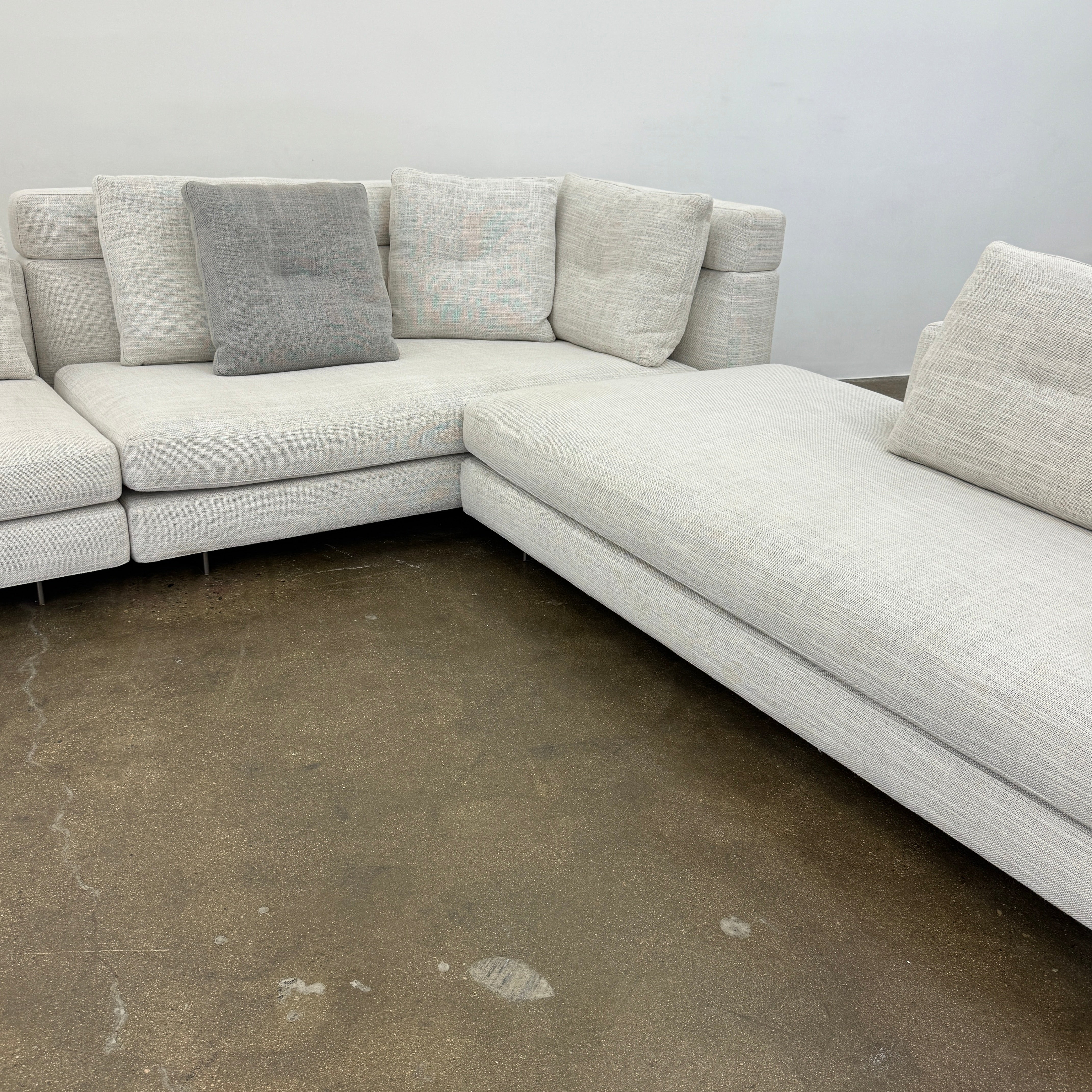 The Minotti Alexander 3 Piece Sectional by Minotti features an L-shaped design in light beige linen blend upholstery with multiple gray and beige throw pillows, set against a plain white background.