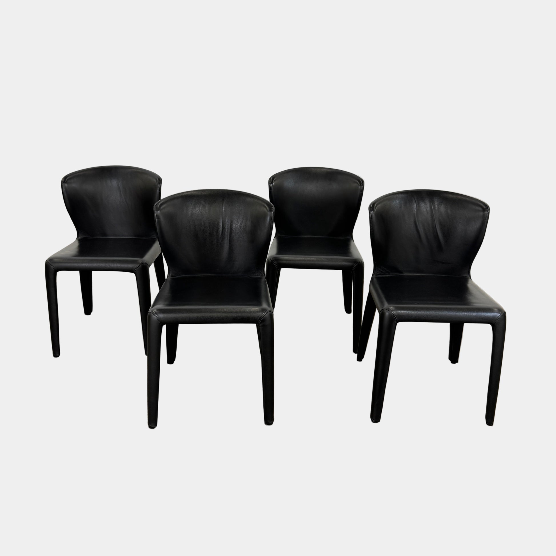 A set of four Cassina Hola Dining Chairs by Cassina, upholstered in black leather, are set in two rows against a plain white background.