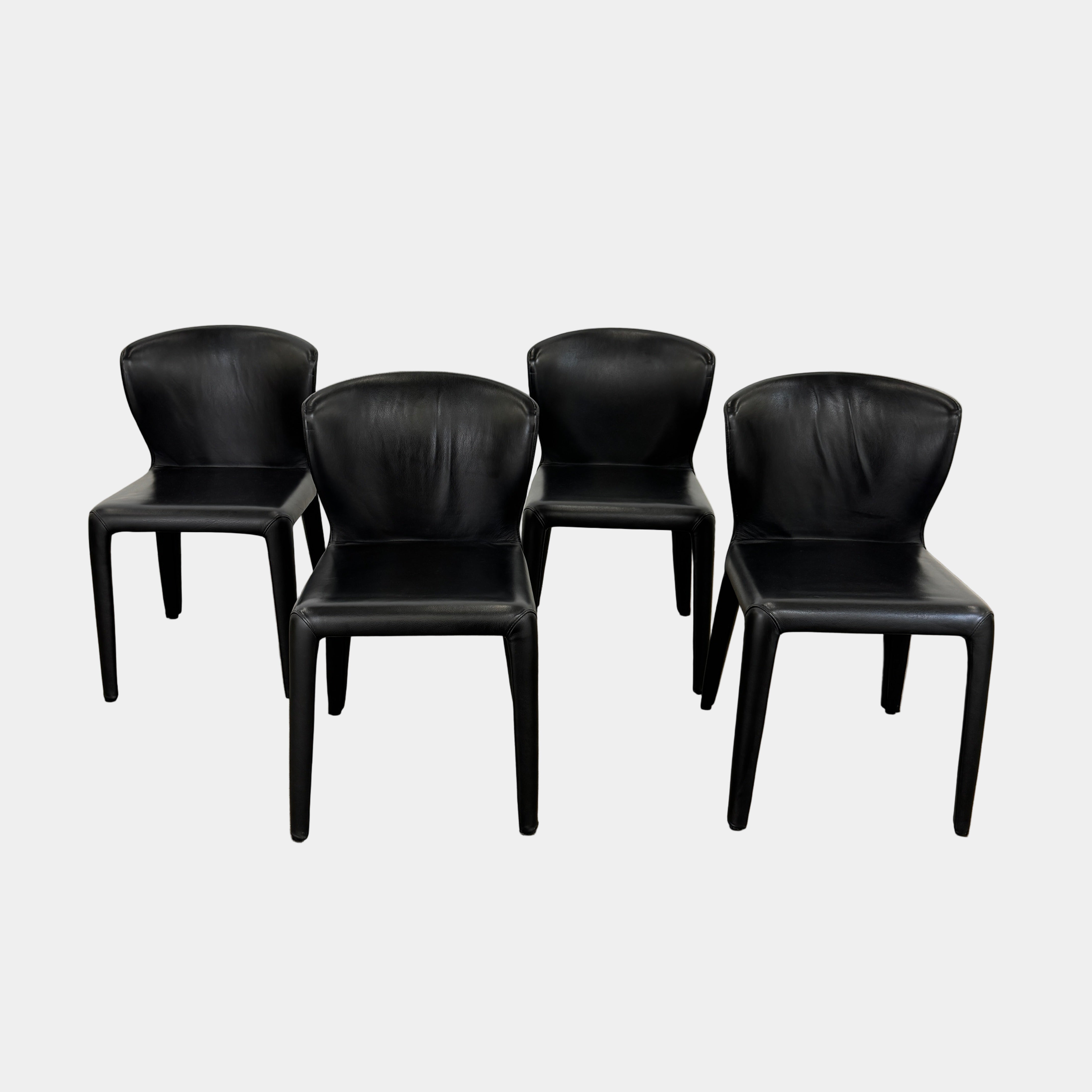 A set of four Cassina Hola Dining Chairs by Cassina, upholstered in black leather, are set in two rows against a plain white background.