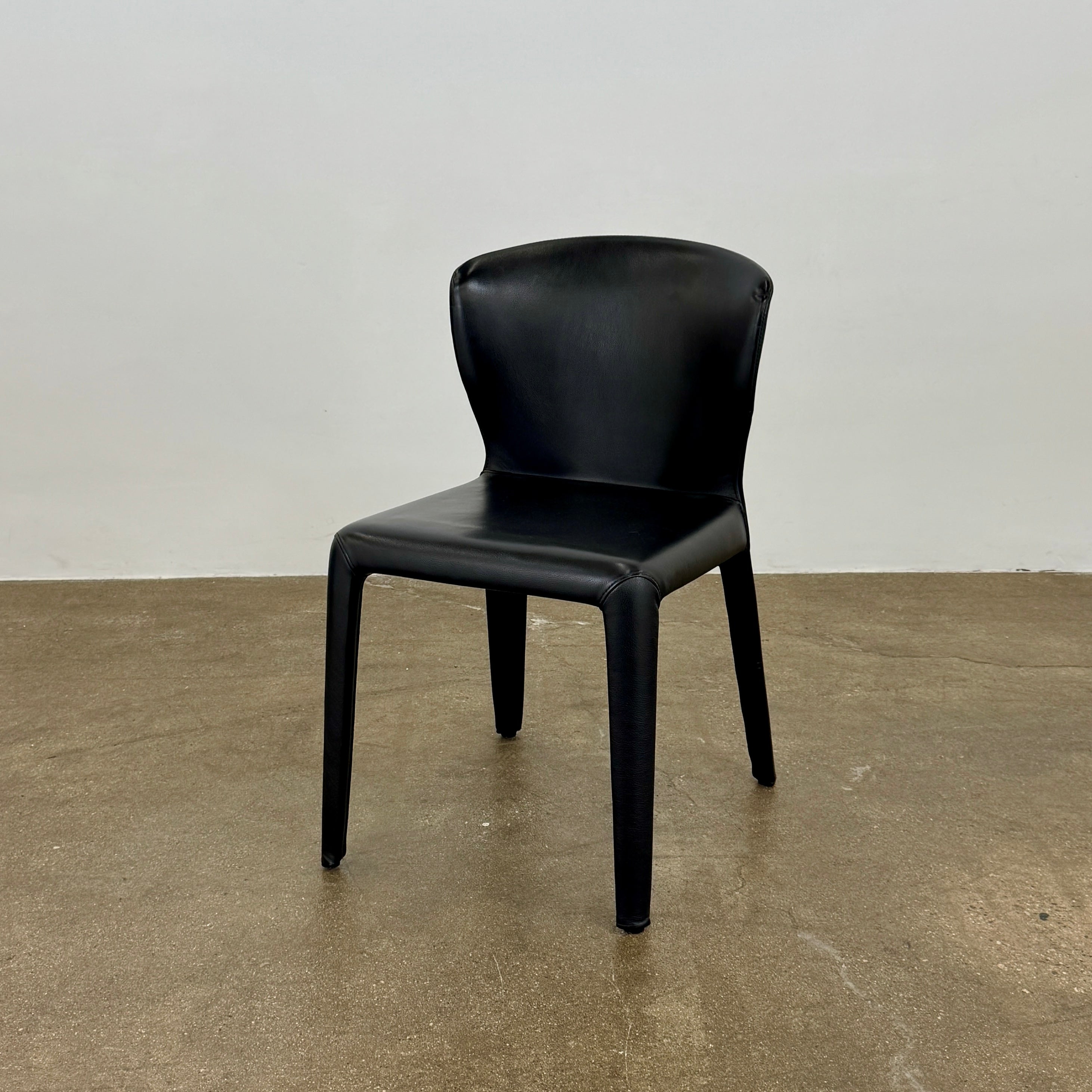 A set of four Cassina Hola Dining Chairs by Cassina, upholstered in black leather, are set in two rows against a plain white background.