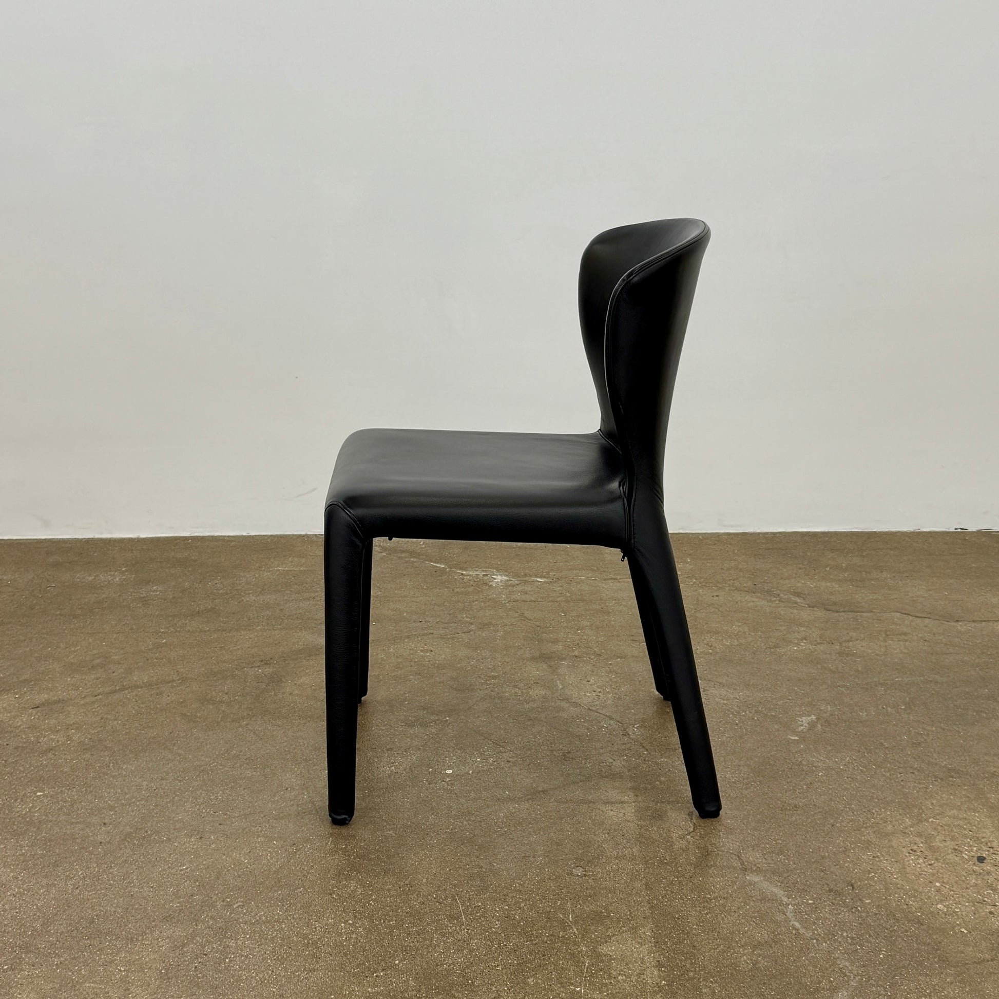 A set of four Cassina Hola Dining Chairs by Cassina, upholstered in black leather, are set in two rows against a plain white background.