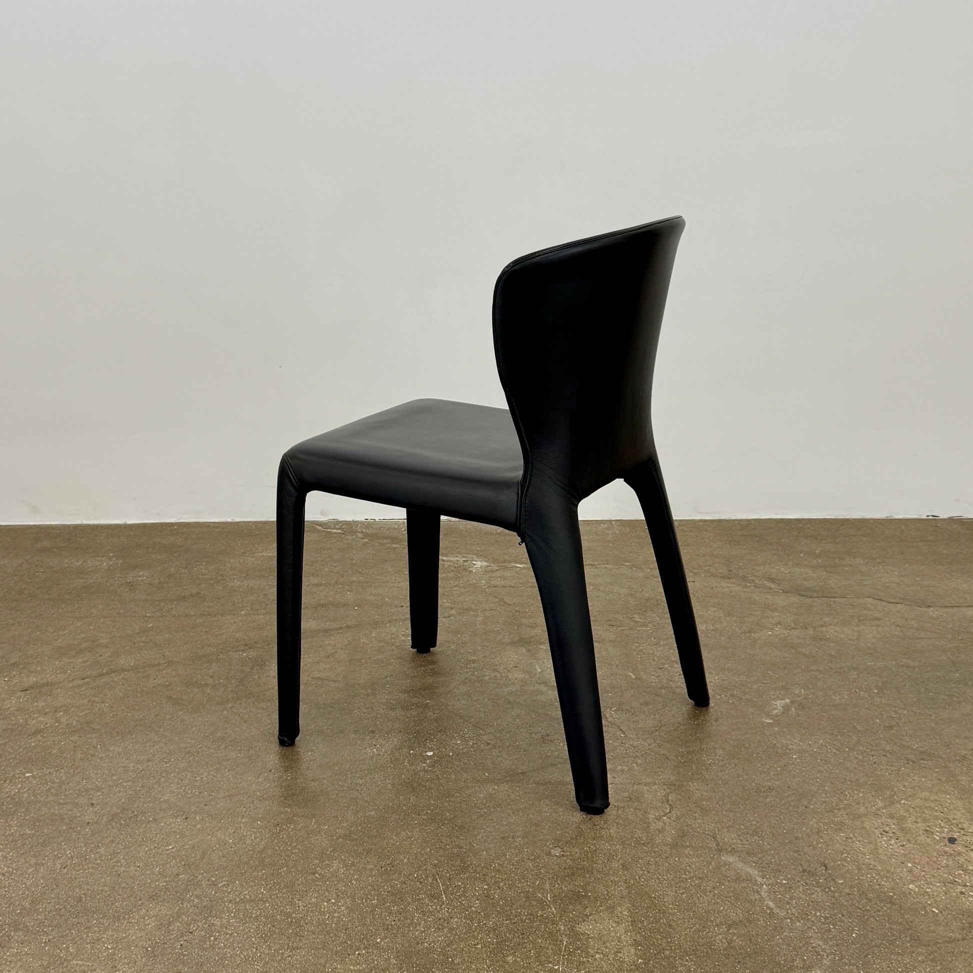 A set of four Cassina Hola Dining Chairs by Cassina, upholstered in black leather, are set in two rows against a plain white background.