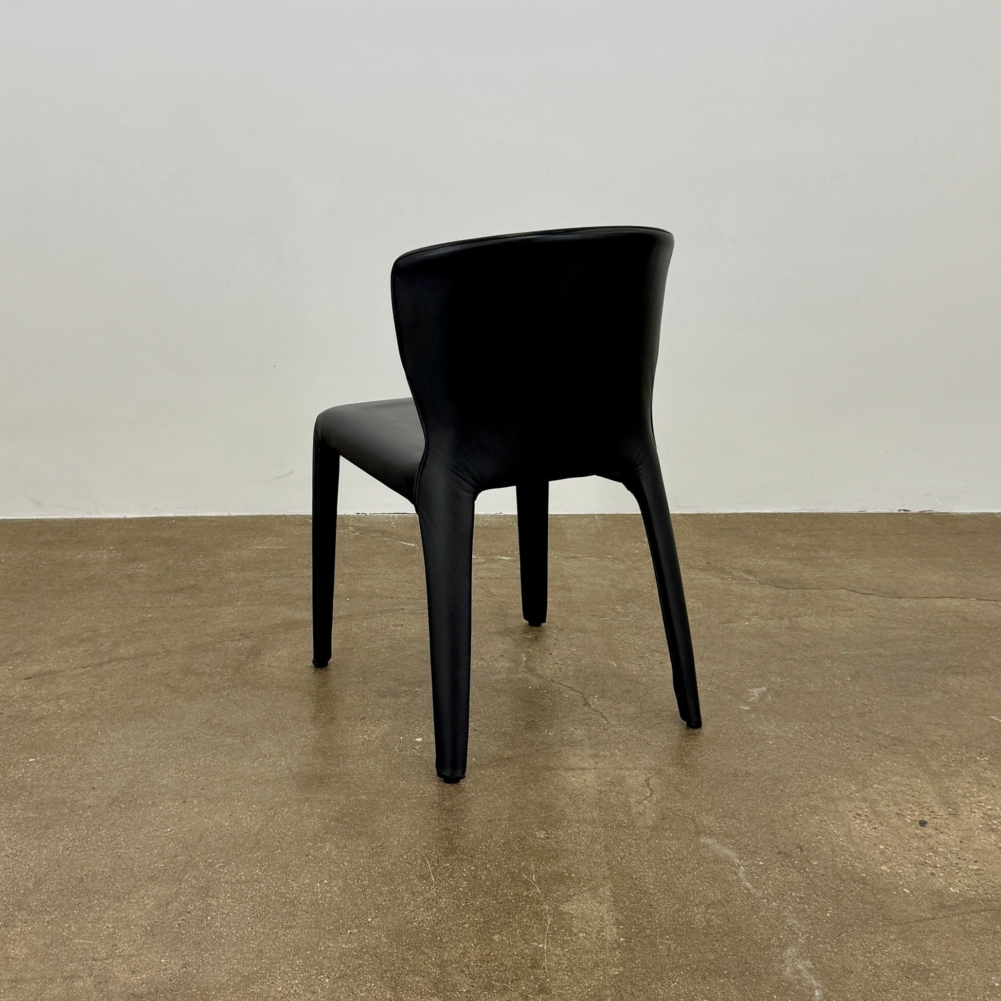A set of four Cassina Hola Dining Chairs by Cassina, upholstered in black leather, are set in two rows against a plain white background.