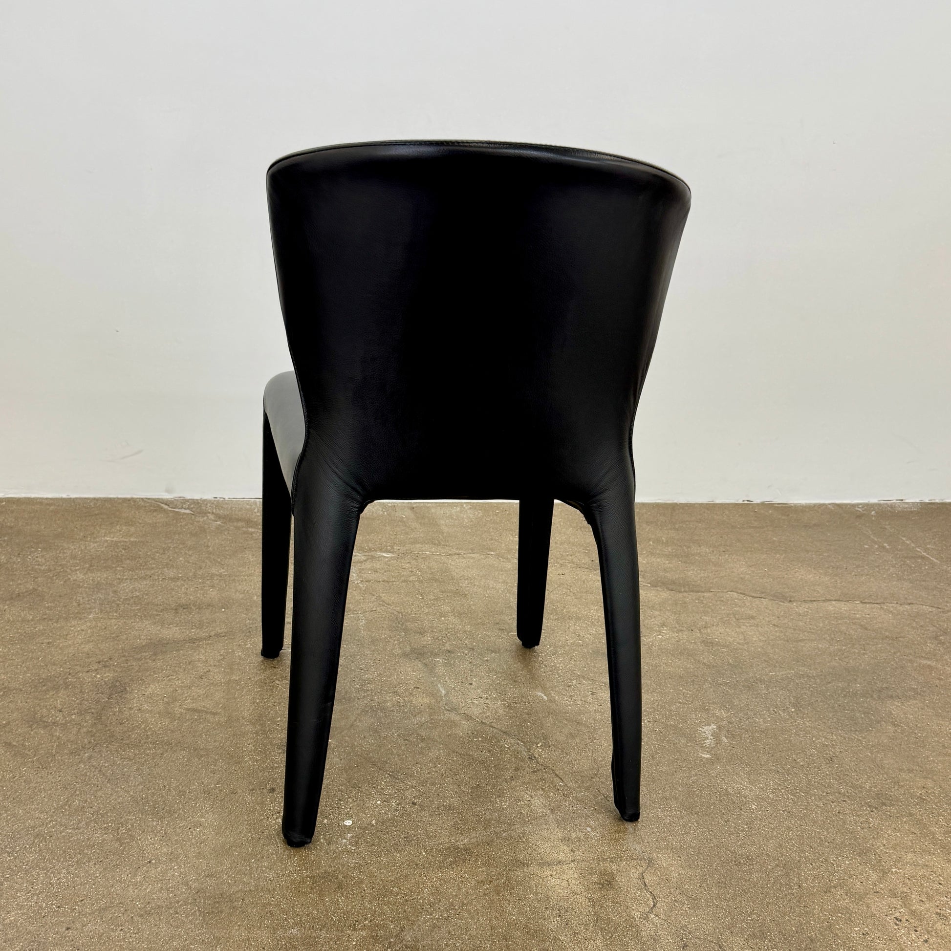 A set of four Cassina Hola Dining Chairs by Cassina, upholstered in black leather, are set in two rows against a plain white background.