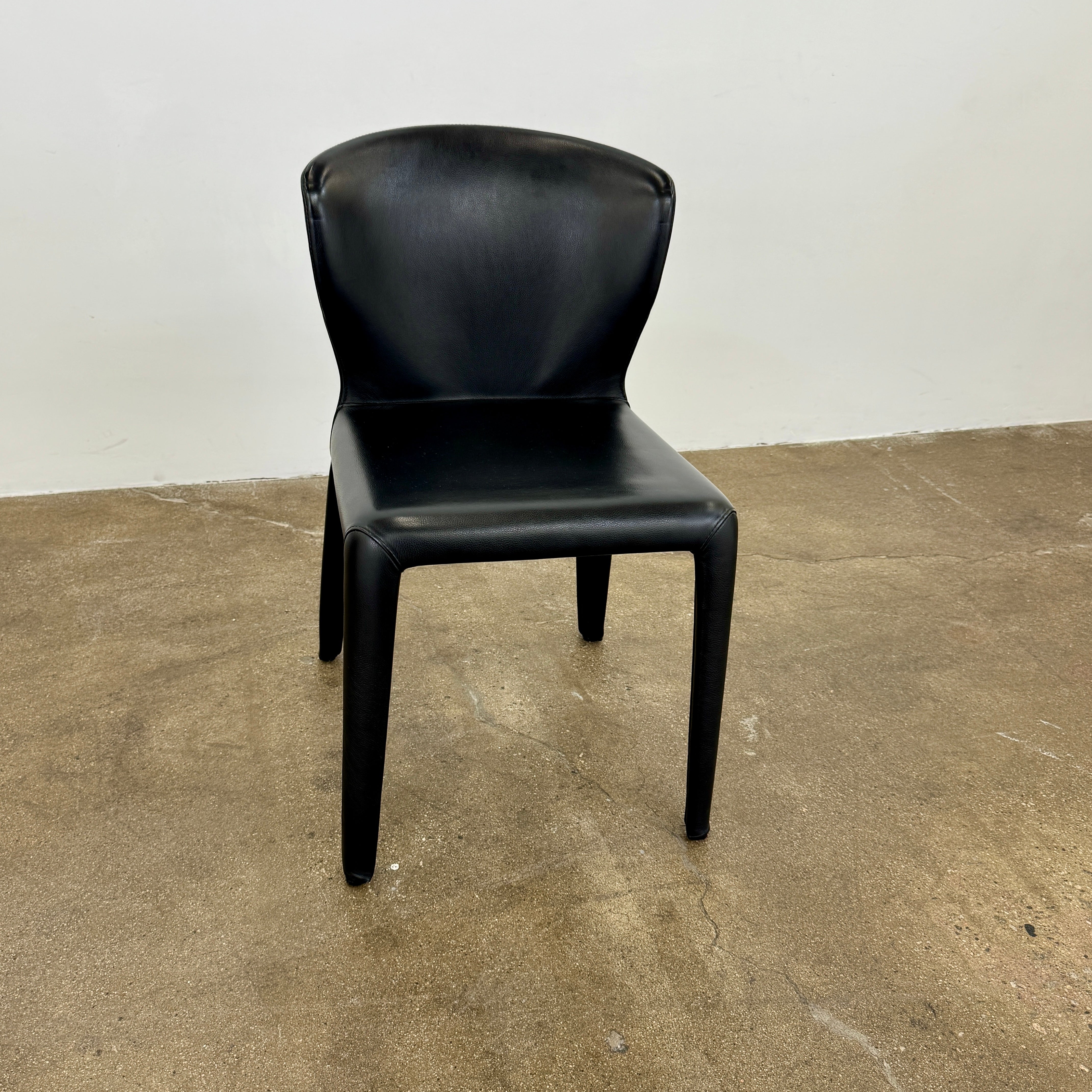 A set of four Cassina Hola Dining Chairs by Cassina, upholstered in black leather, are set in two rows against a plain white background.