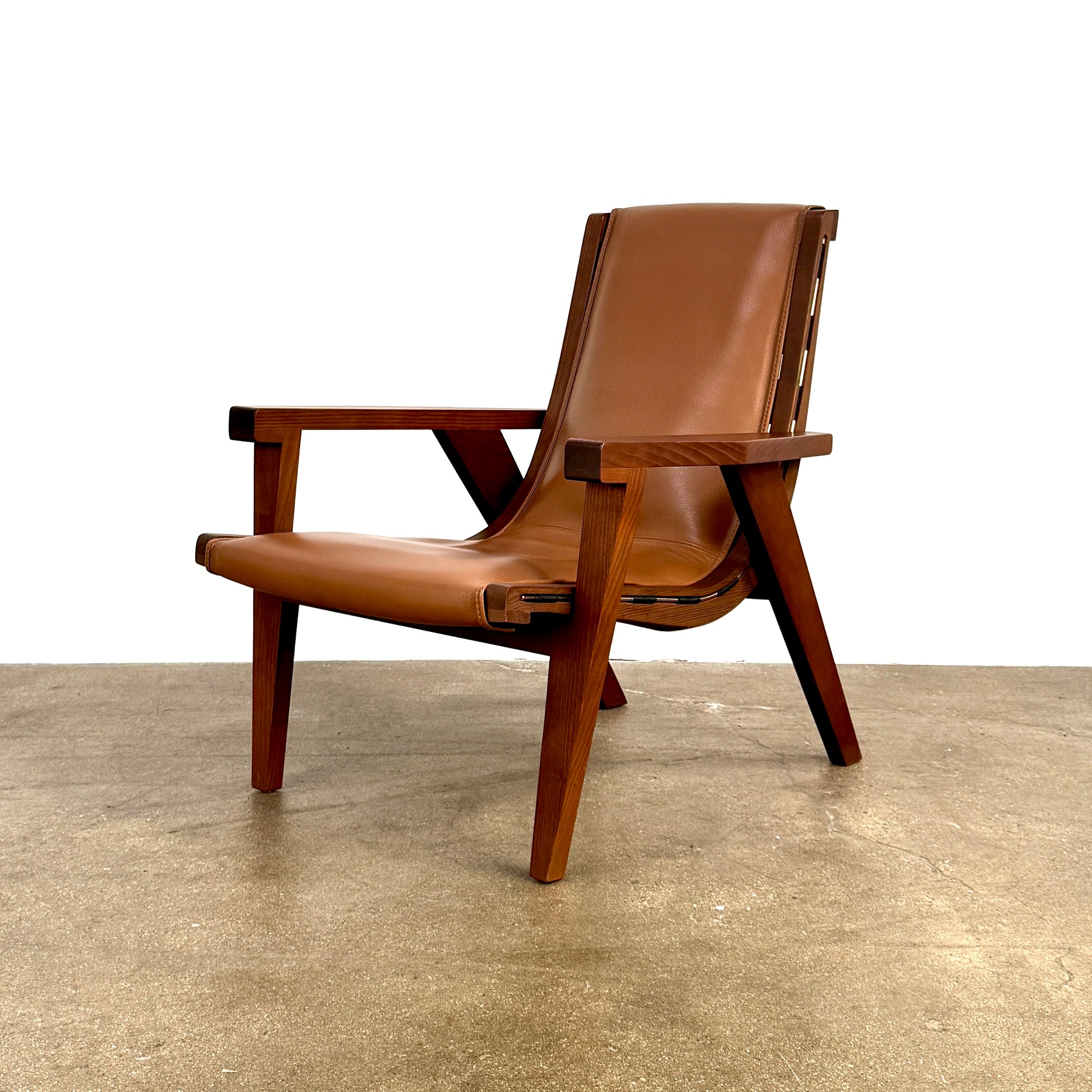 A contemporary B&B Italia JJ Armchair with brown leather seat and backrest, angular armrests, and a dark wooden frame, designed by Antonio Citterio. Set against a plain white background.