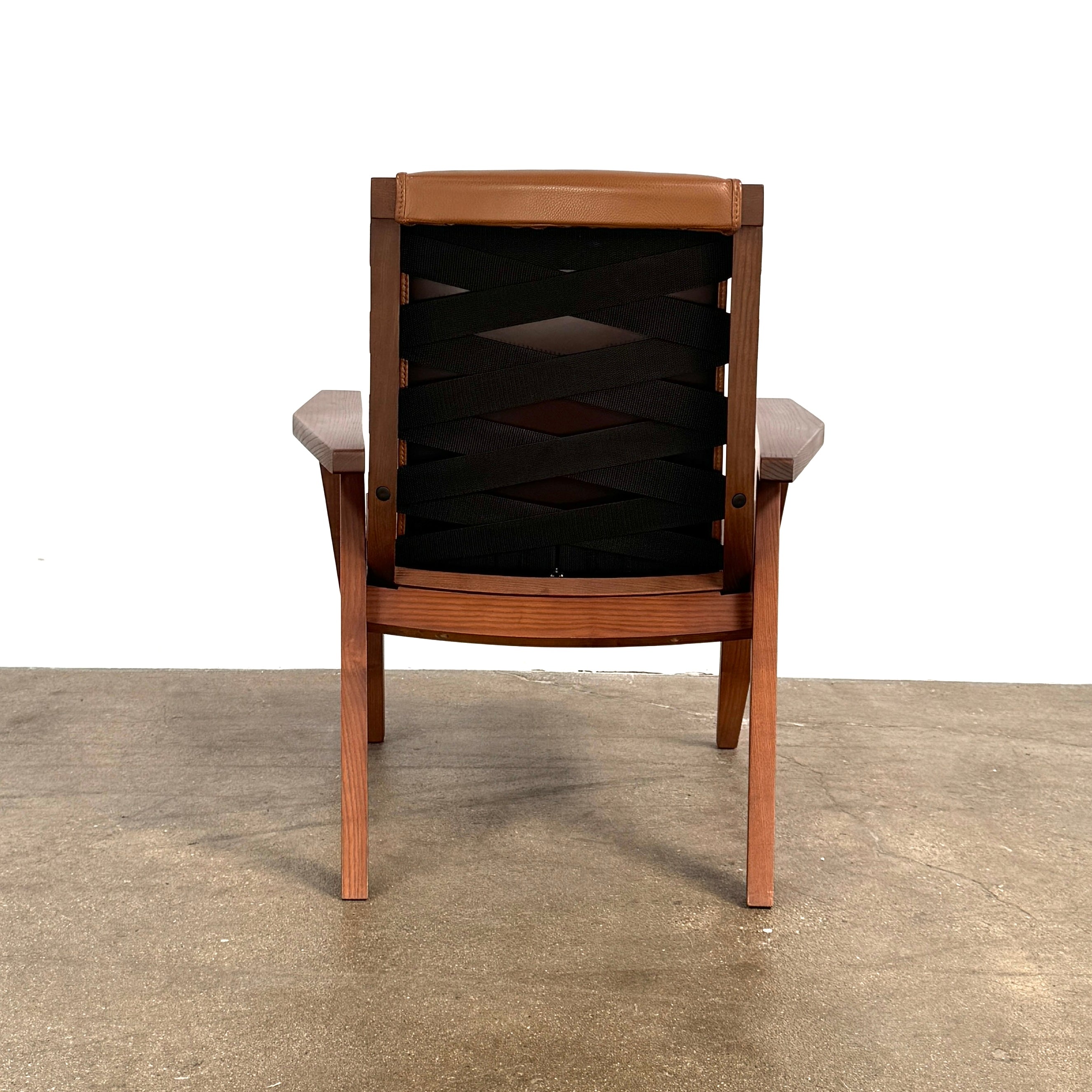 A contemporary B&B Italia JJ Armchair with brown leather seat and backrest, angular armrests, and a dark wooden frame, designed by Antonio Citterio. Set against a plain white background.
