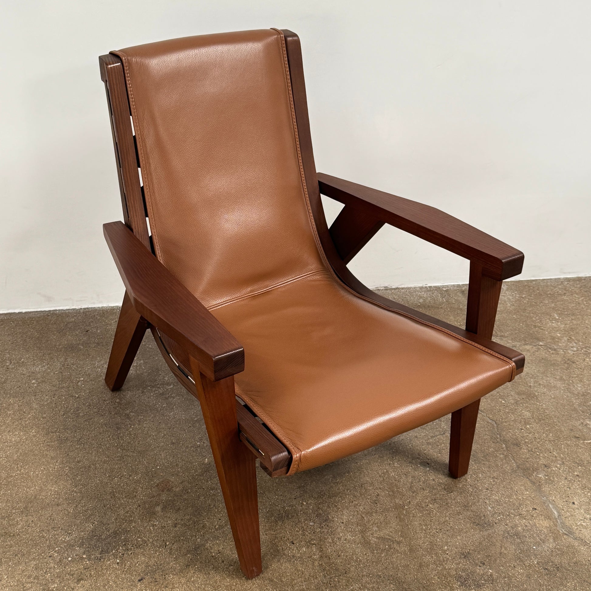 A contemporary B&B Italia JJ Armchair with brown leather seat and backrest, angular armrests, and a dark wooden frame, designed by Antonio Citterio. Set against a plain white background.