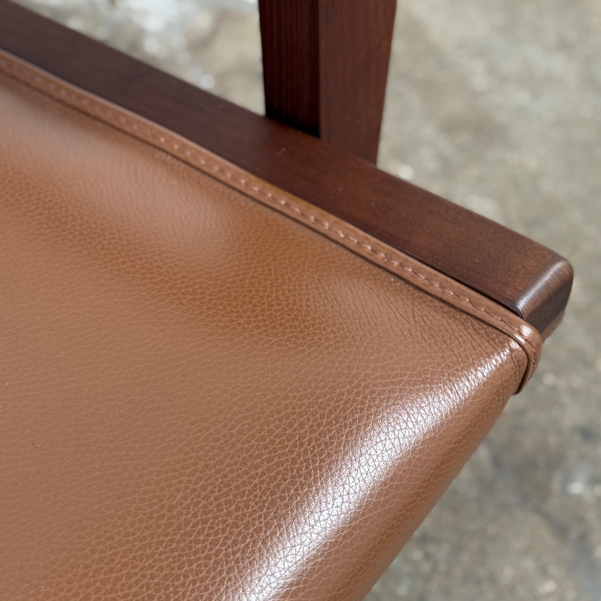 A contemporary B&B Italia JJ Armchair with brown leather seat and backrest, angular armrests, and a dark wooden frame, designed by Antonio Citterio. Set against a plain white background.