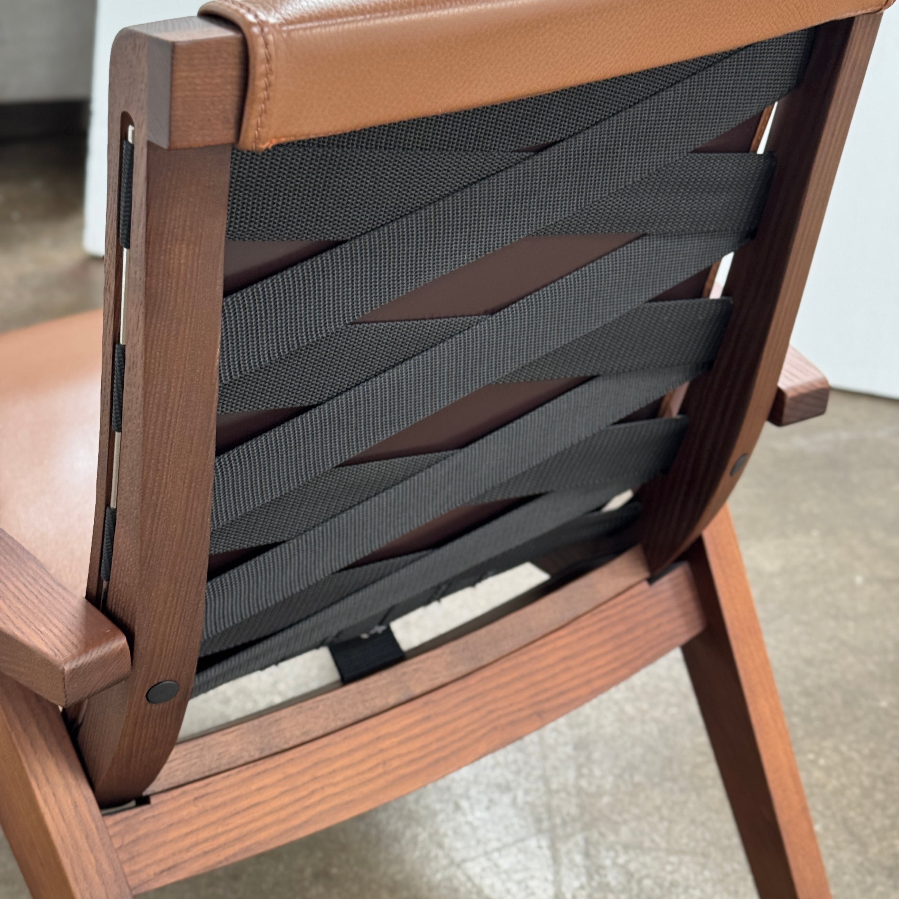 A contemporary B&B Italia JJ Armchair with brown leather seat and backrest, angular armrests, and a dark wooden frame, designed by Antonio Citterio. Set against a plain white background.