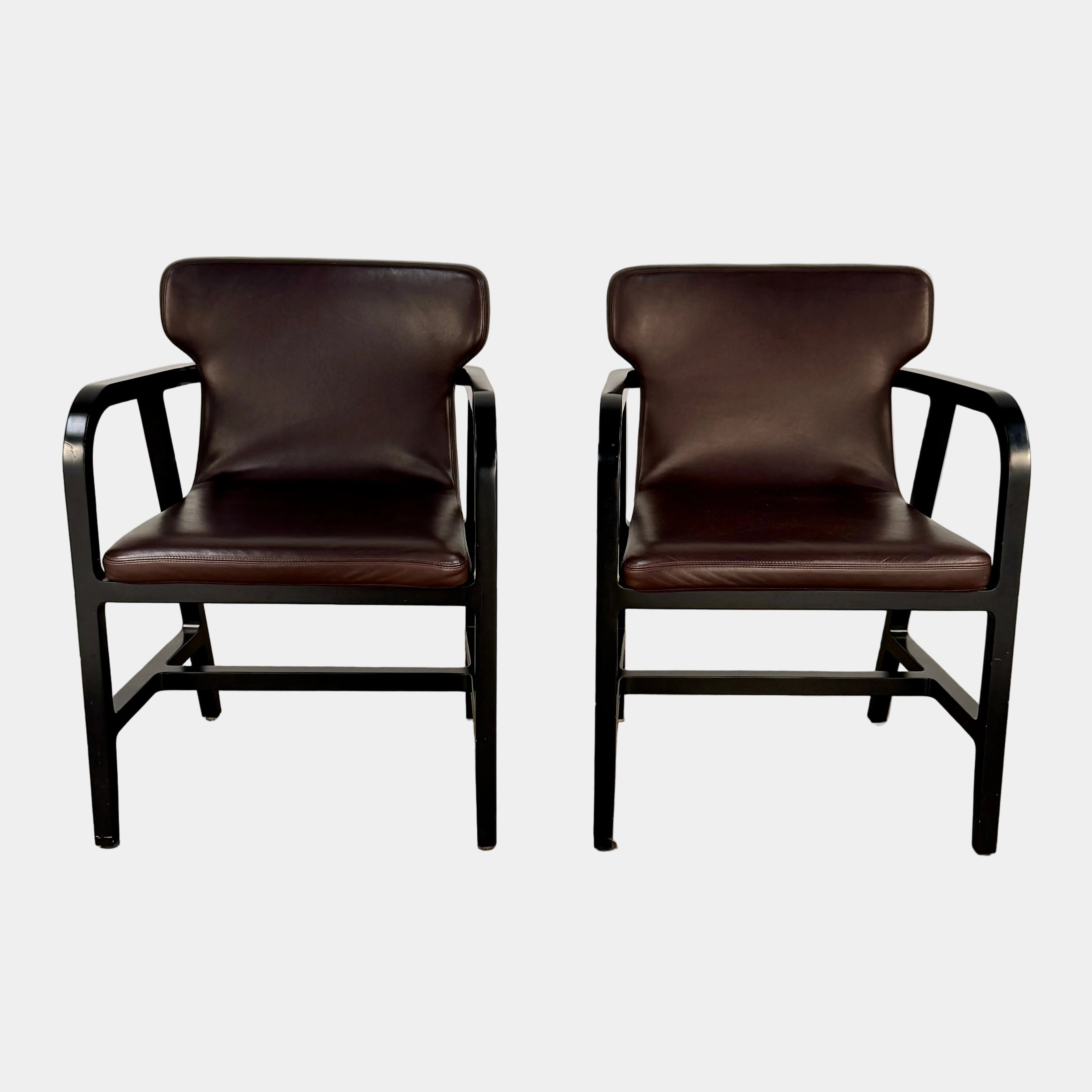 A pair of Maxalto Fulgens Armchair set (2) by Maxalto, in dark brown leather with black wooden frames, are placed side by side against a plain white background.