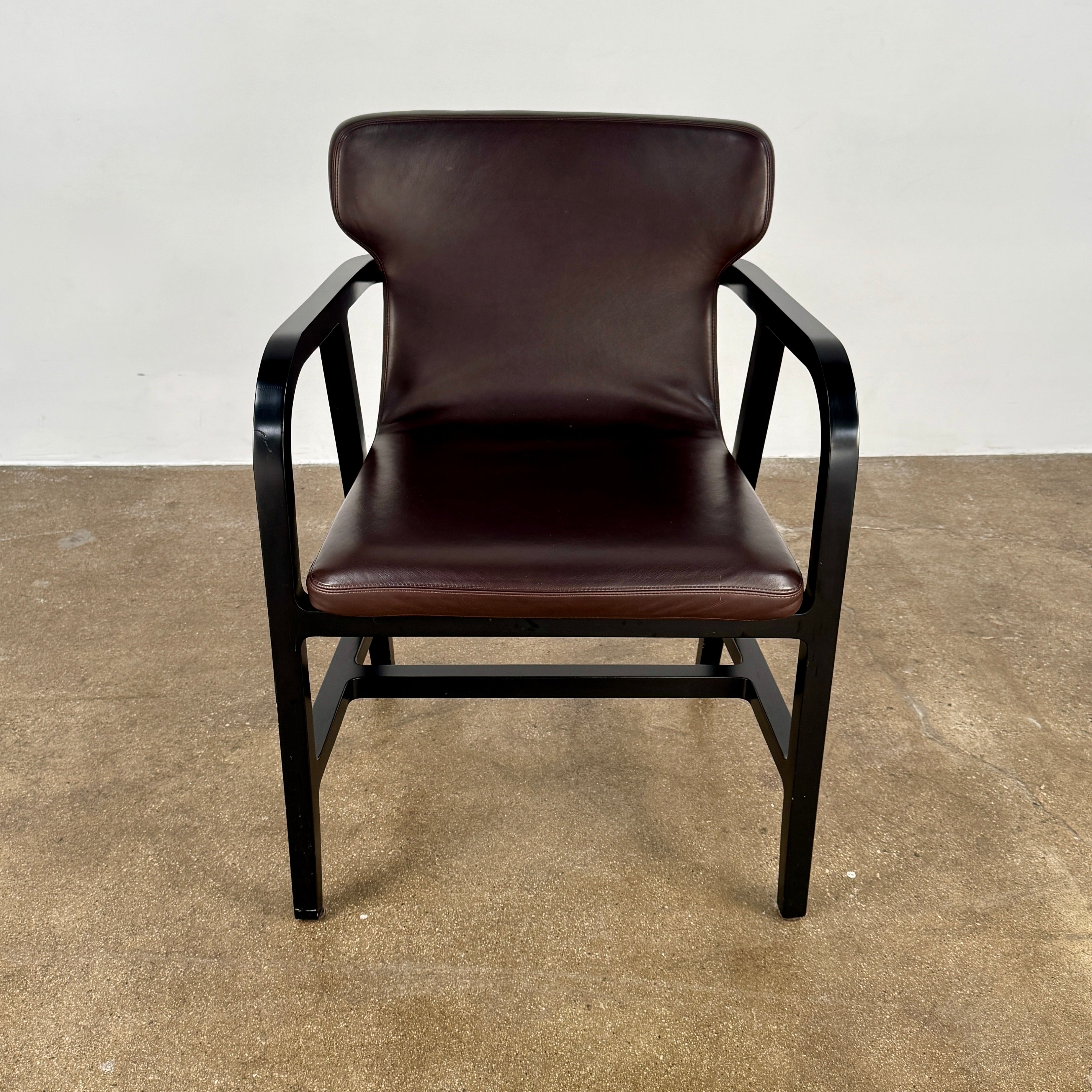 A pair of Maxalto Fulgens Armchair set (2) by Maxalto, in dark brown leather with black wooden frames, are placed side by side against a plain white background.