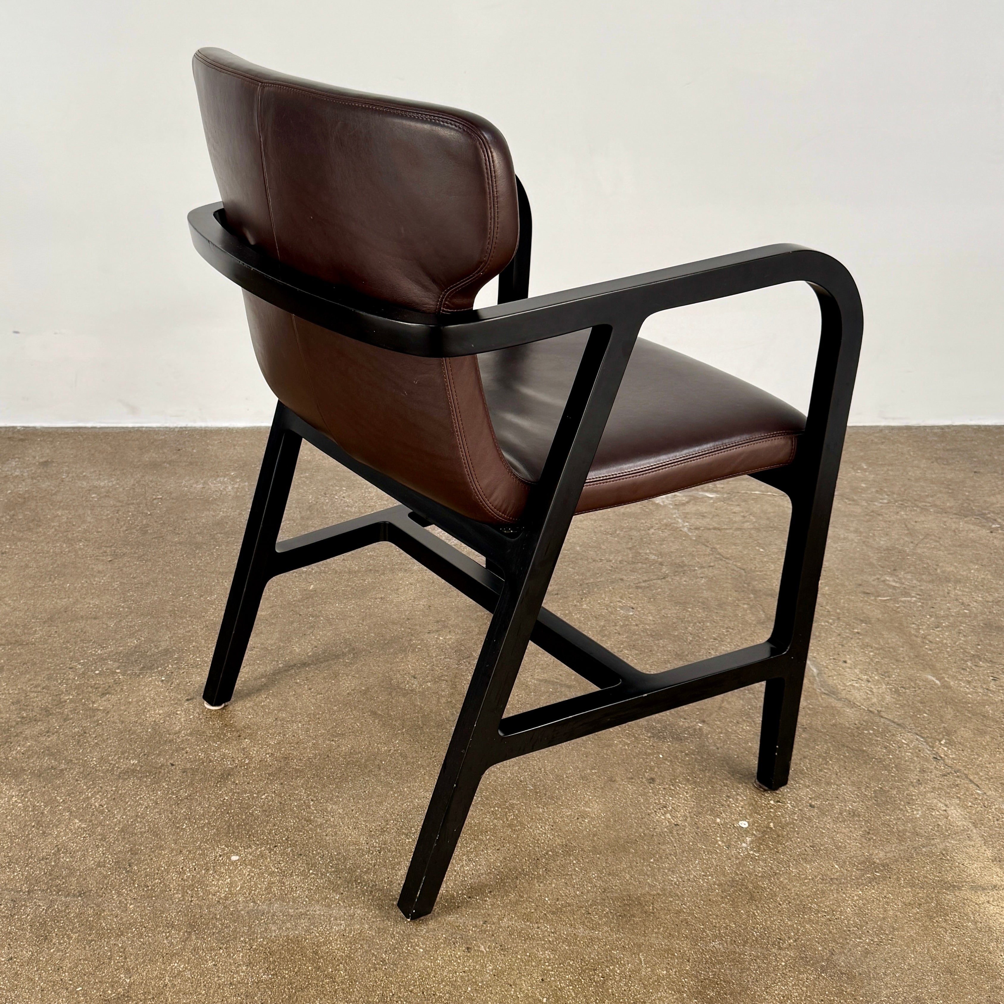 A pair of Maxalto Fulgens Armchair set (2) by Maxalto, in dark brown leather with black wooden frames, are placed side by side against a plain white background.