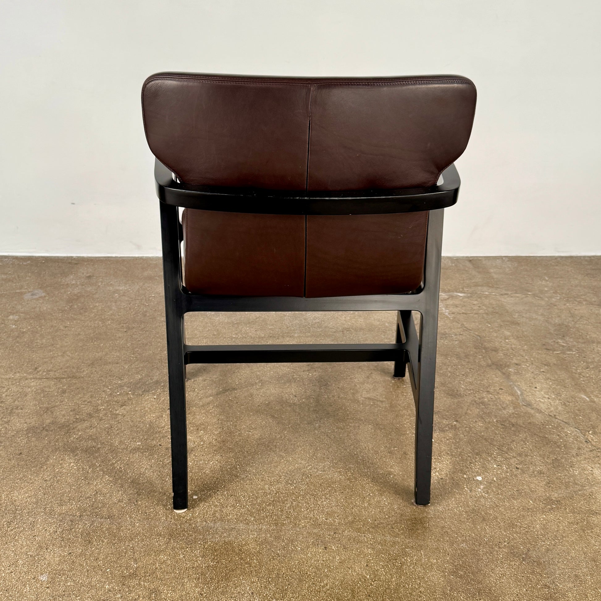 A pair of Maxalto Fulgens Armchair set (2) by Maxalto, in dark brown leather with black wooden frames, are placed side by side against a plain white background.