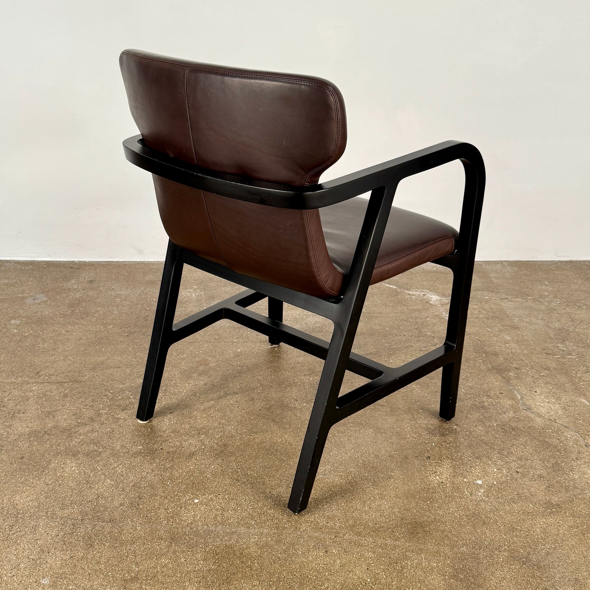 A pair of Maxalto Fulgens Armchair set (2) by Maxalto, in dark brown leather with black wooden frames, are placed side by side against a plain white background.