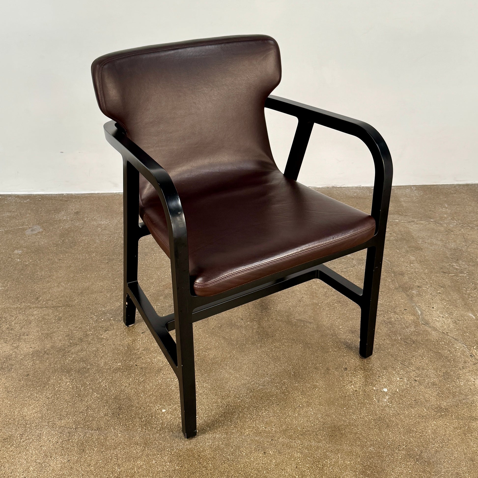A pair of Maxalto Fulgens Armchair set (2) by Maxalto, in dark brown leather with black wooden frames, are placed side by side against a plain white background.