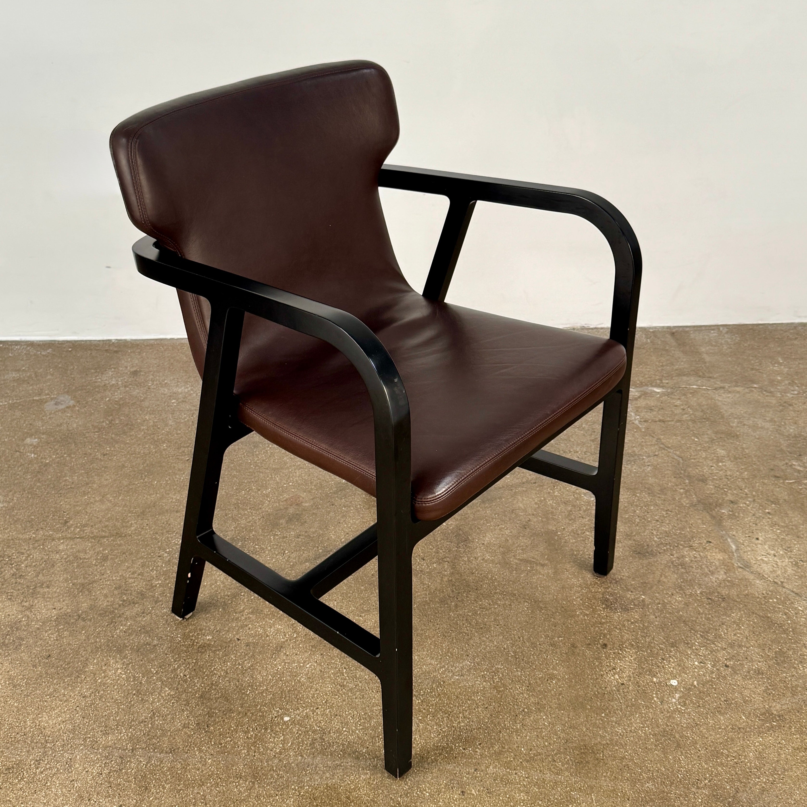 A pair of Maxalto Fulgens Armchair set (2) by Maxalto, in dark brown leather with black wooden frames, are placed side by side against a plain white background.