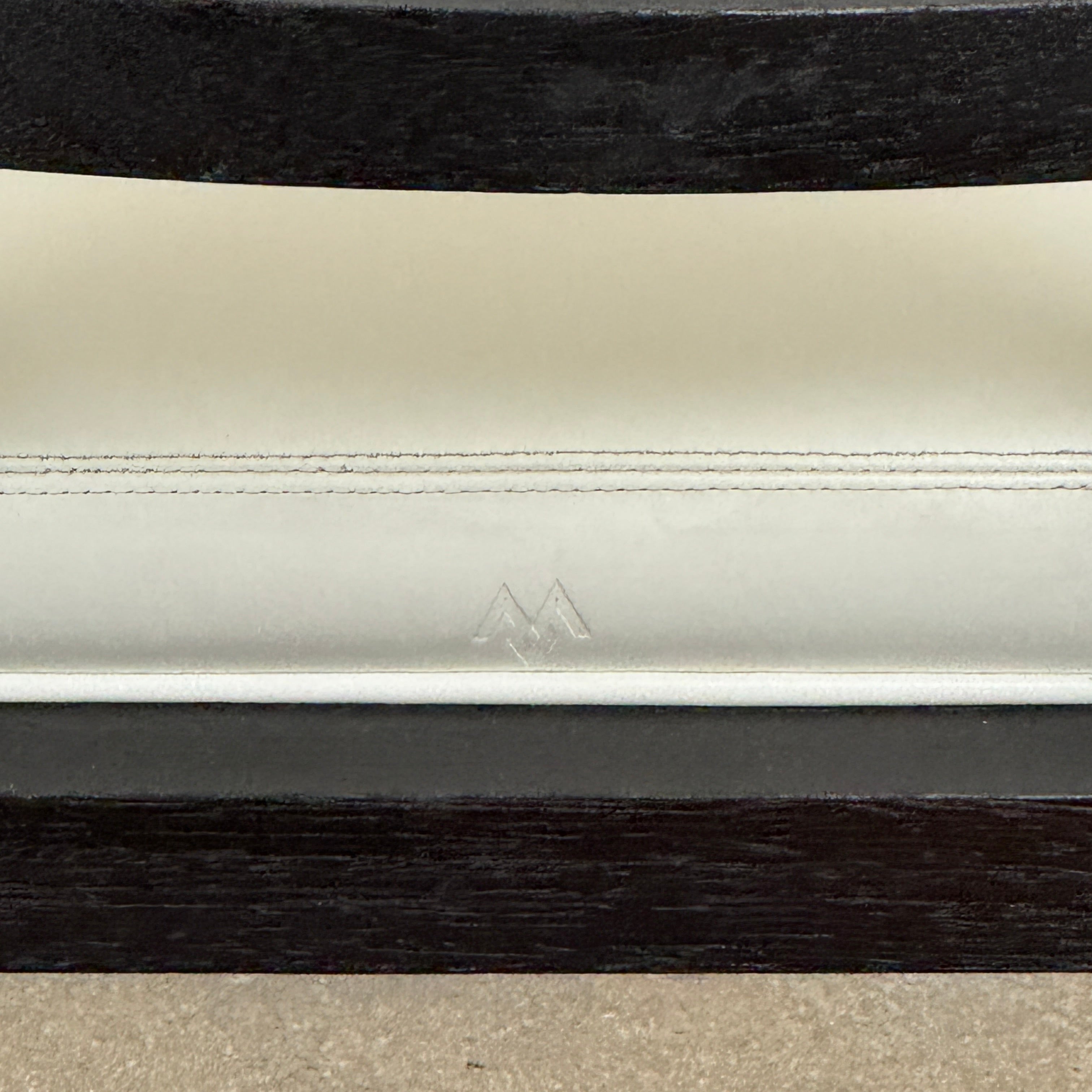 A Maxalto Teti Dining Chair from a set of 6, featuring a black frame with white upholstered seat and backrest, stands on a brown concrete floor against a plain light gray wall.