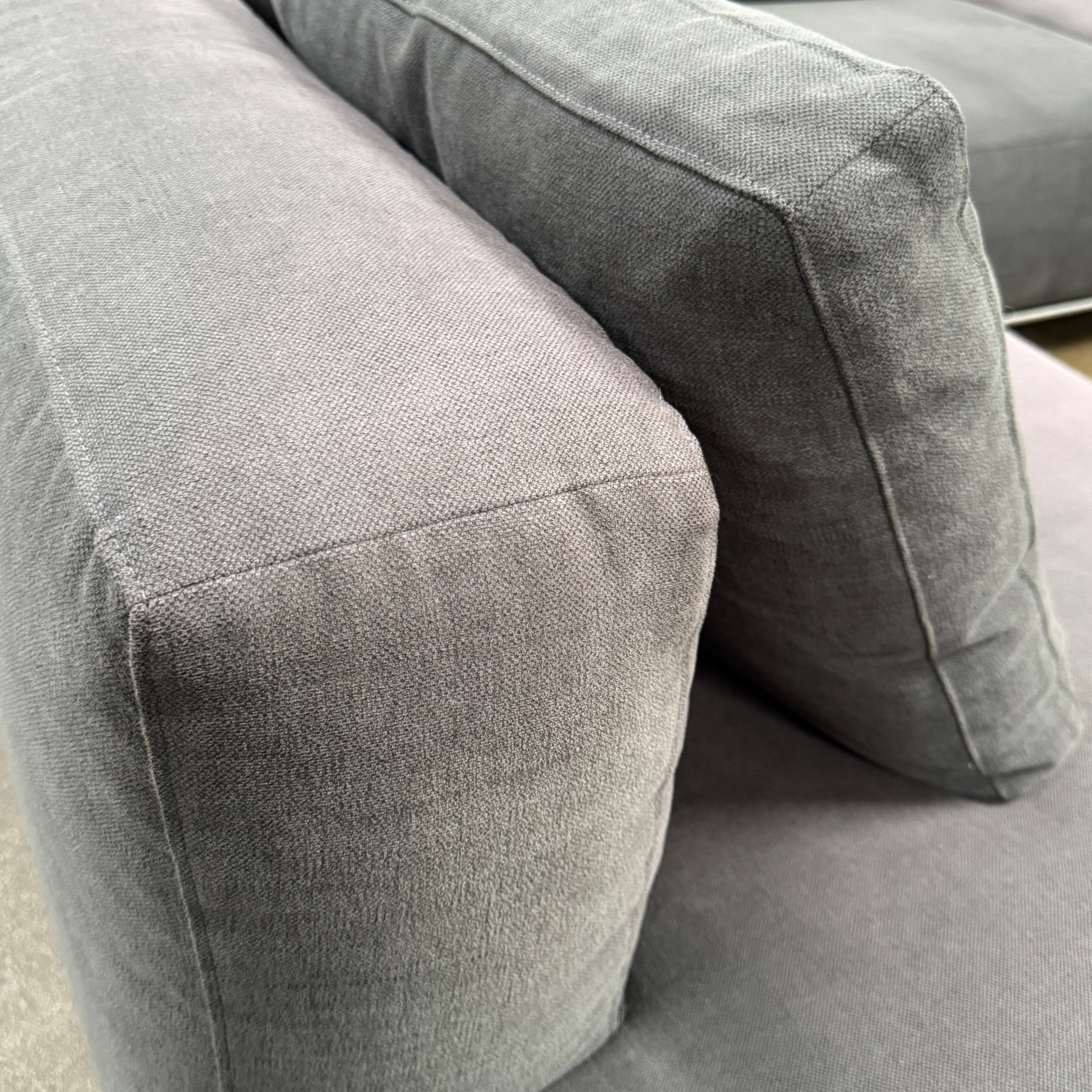 The Cassina Mex Hi Modular Sofa by Cassina features dark gray recycled fiber upholstery, metal legs, multiple cushions, and an integrated wooden side table, shown against a white background.