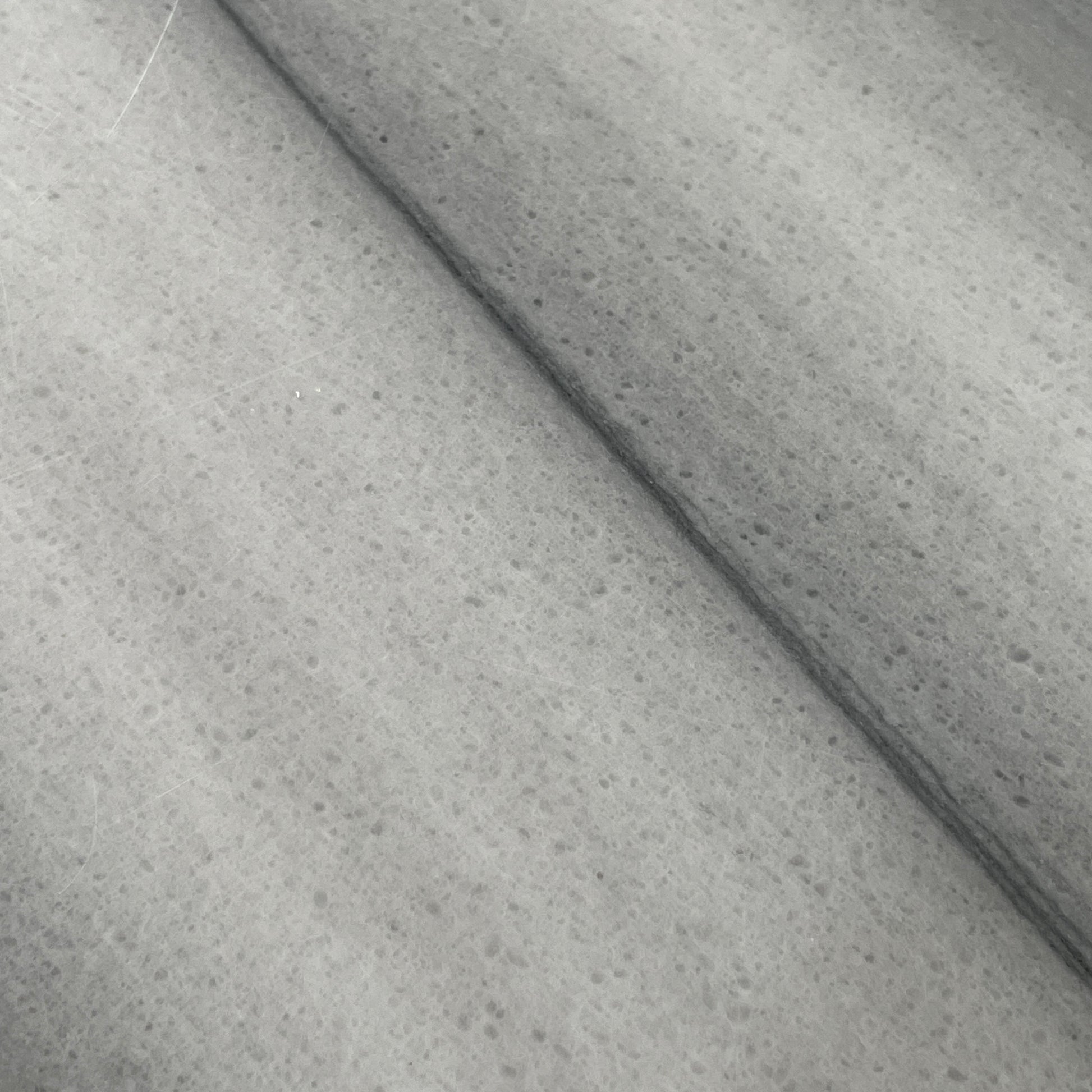 The Lievo Home Modern Studio Ingrid Coffee Table has a glossy marble top with white and gray stripes and a polished stainless steel base, shown on a bare concrete floor against a plain white wall.