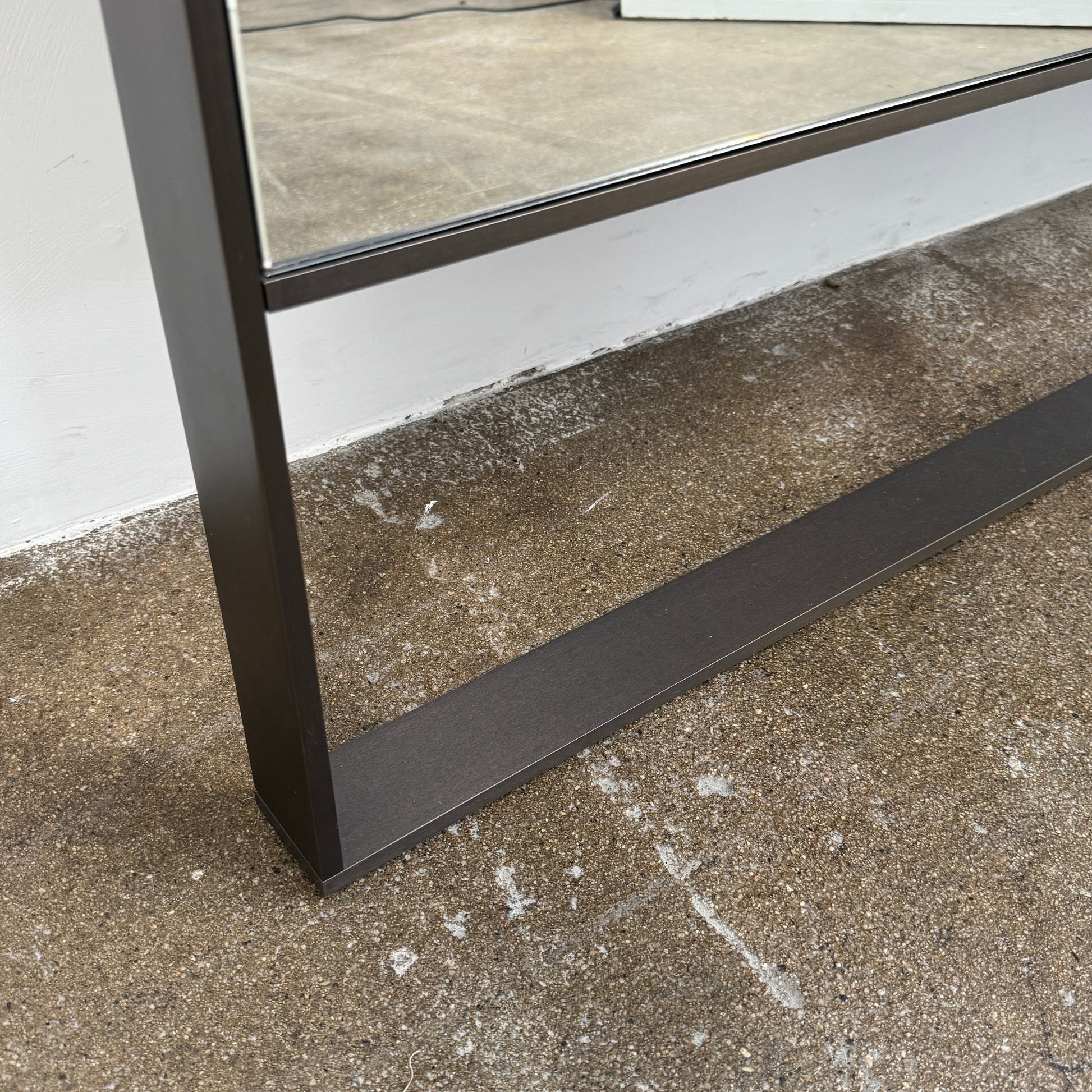 The Maxalto Psiche Leaning Mirror by Maxalto features a large rectangular shape, a slim dark frame, and a minimalist base, shown against a plain white background.