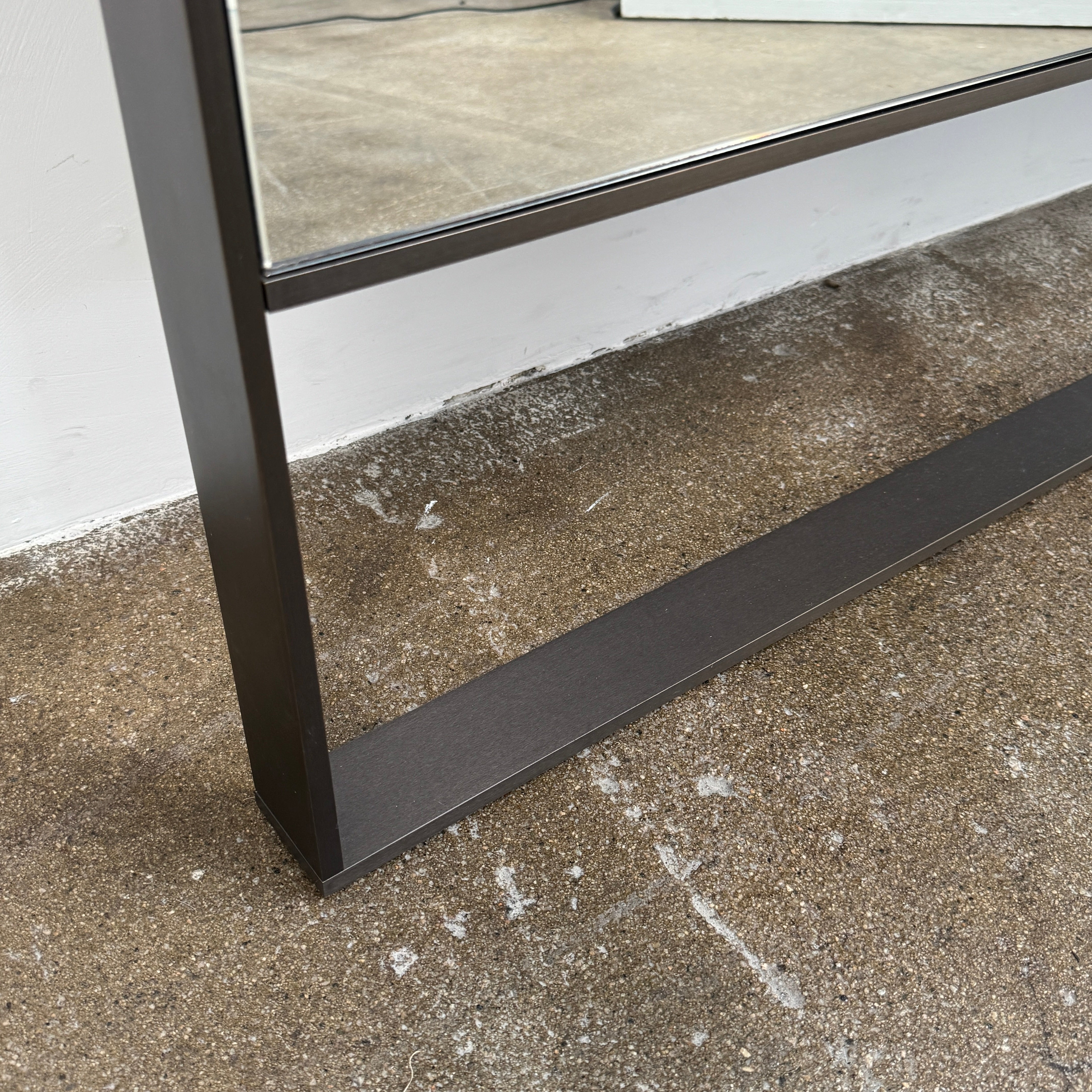 The Maxalto Psiche Leaning Mirror by Maxalto features a large rectangular shape, a slim dark frame, and a minimalist base, shown against a plain white background.