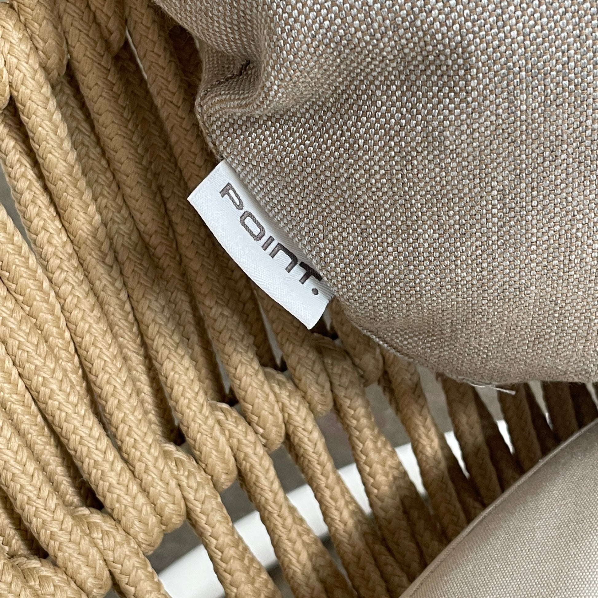 The Point 1920 Weave Hanging Swing with Base by Modern Resale features a white metal frame, wicker seat, and beige cushions, shown freestanding and isolated on a plain white background.