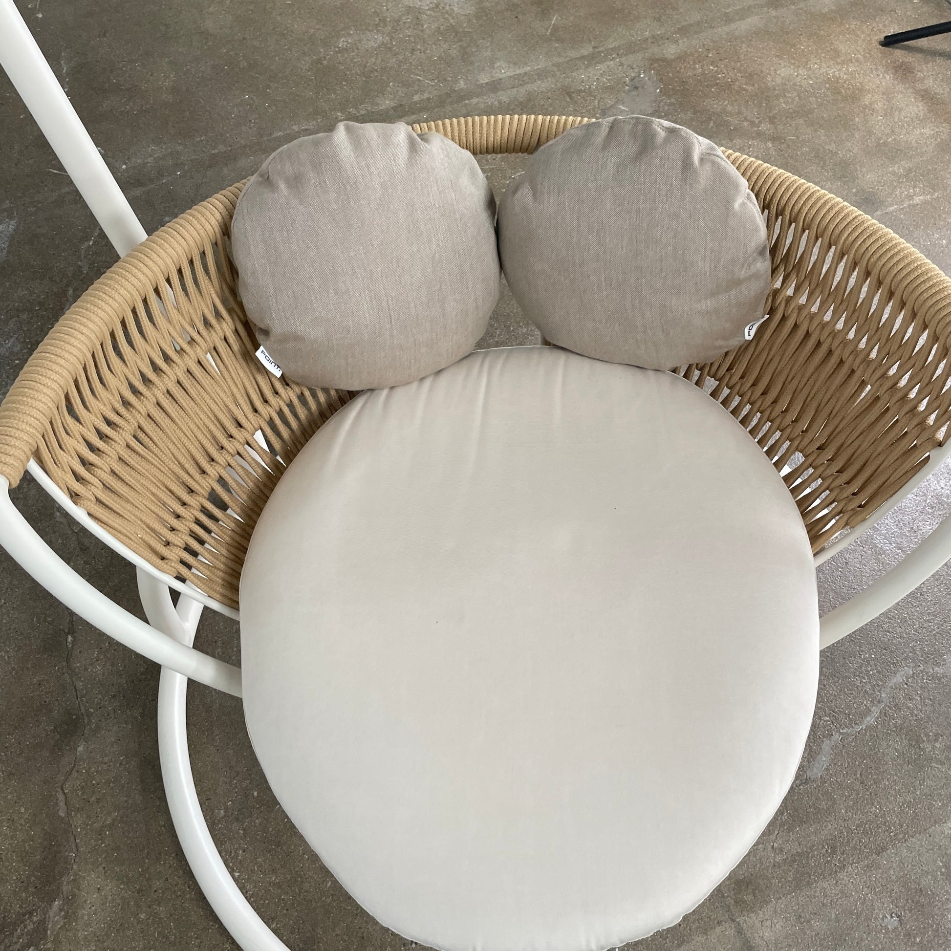 The Point 1920 Weave Hanging Swing with Base by Modern Resale features a white metal frame, wicker seat, and beige cushions, shown freestanding and isolated on a plain white background.