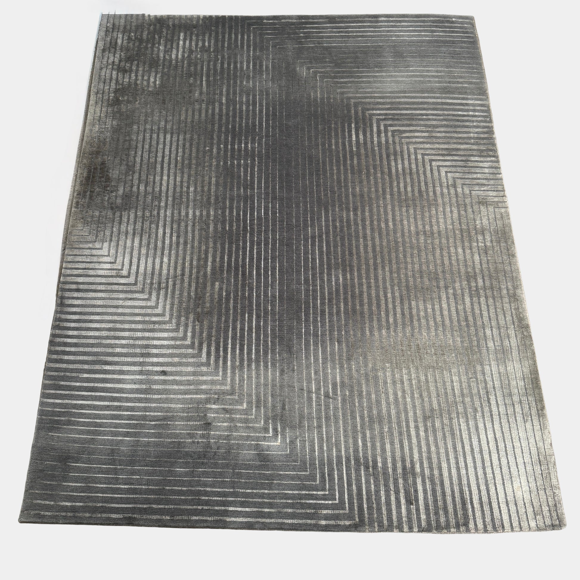 The Delinear Detour Rug 8 x 10 by Delinear features a contemporary rectangular design with a gradient gray pattern and angular geometric lines arranged in a stepped motif.