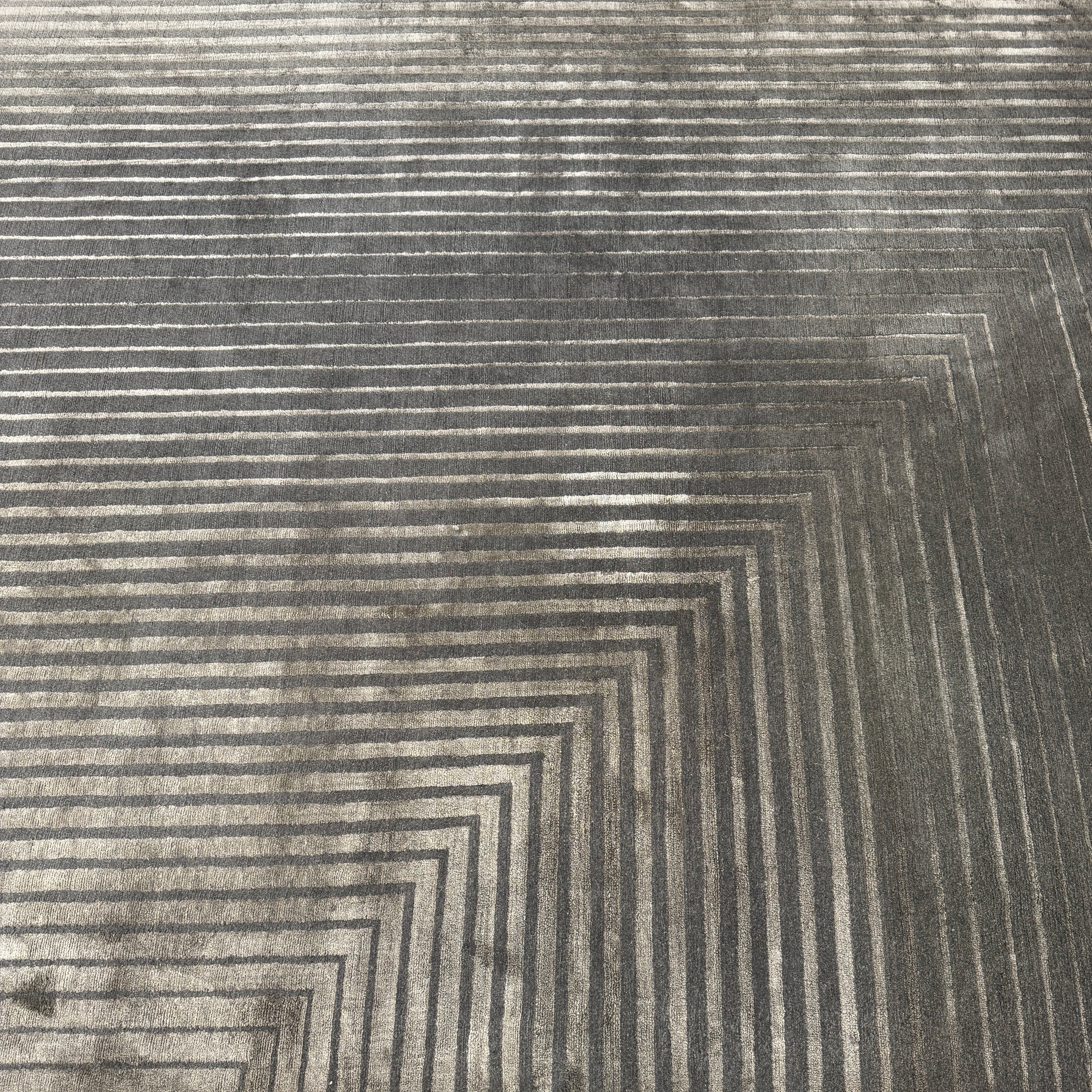 The Delinear Detour Rug 8 x 10 by Delinear features a contemporary rectangular design with a gradient gray pattern and angular geometric lines arranged in a stepped motif.