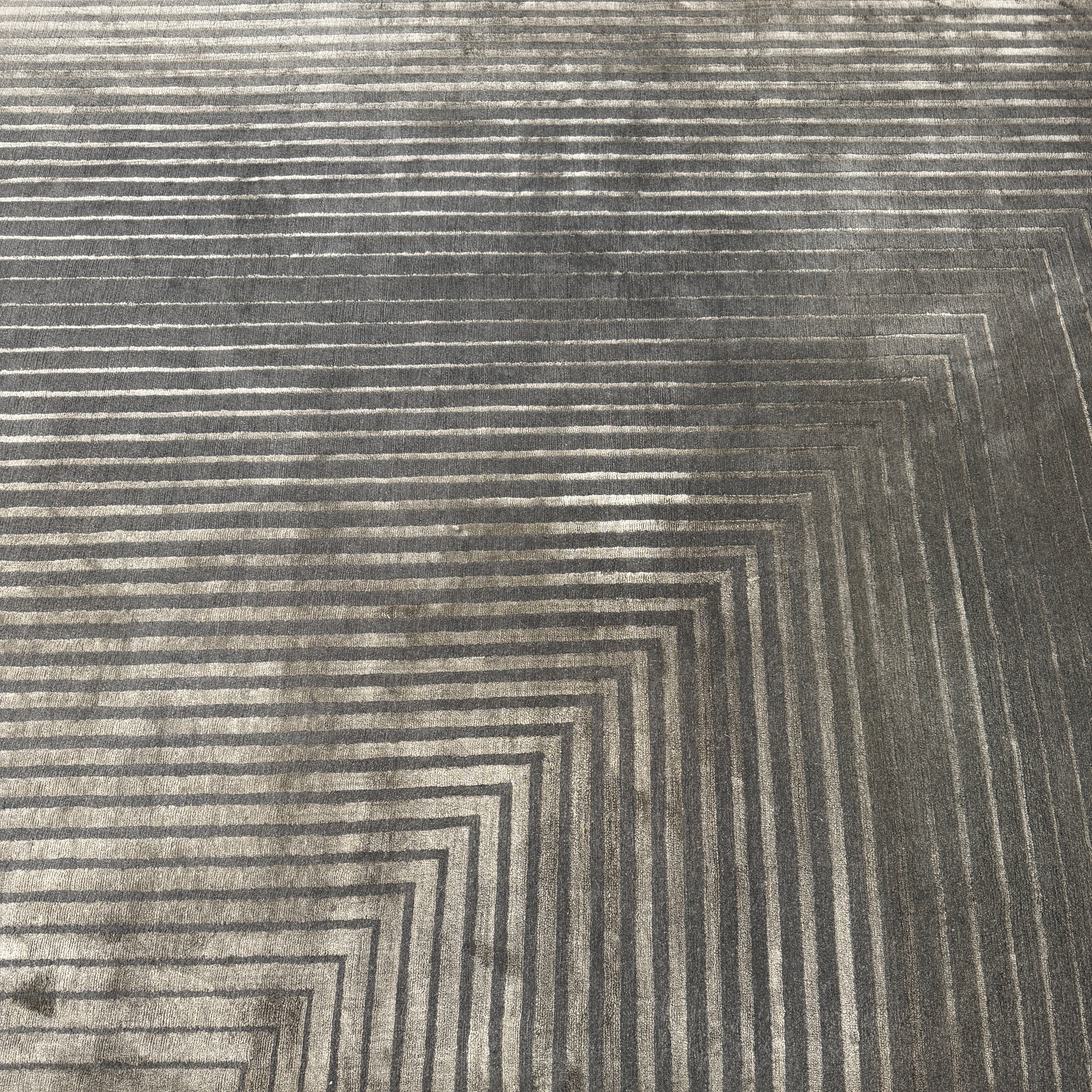 The Delinear Detour Rug 8 x 10 by Delinear features a contemporary rectangular design with a gradient gray pattern and angular geometric lines arranged in a stepped motif.