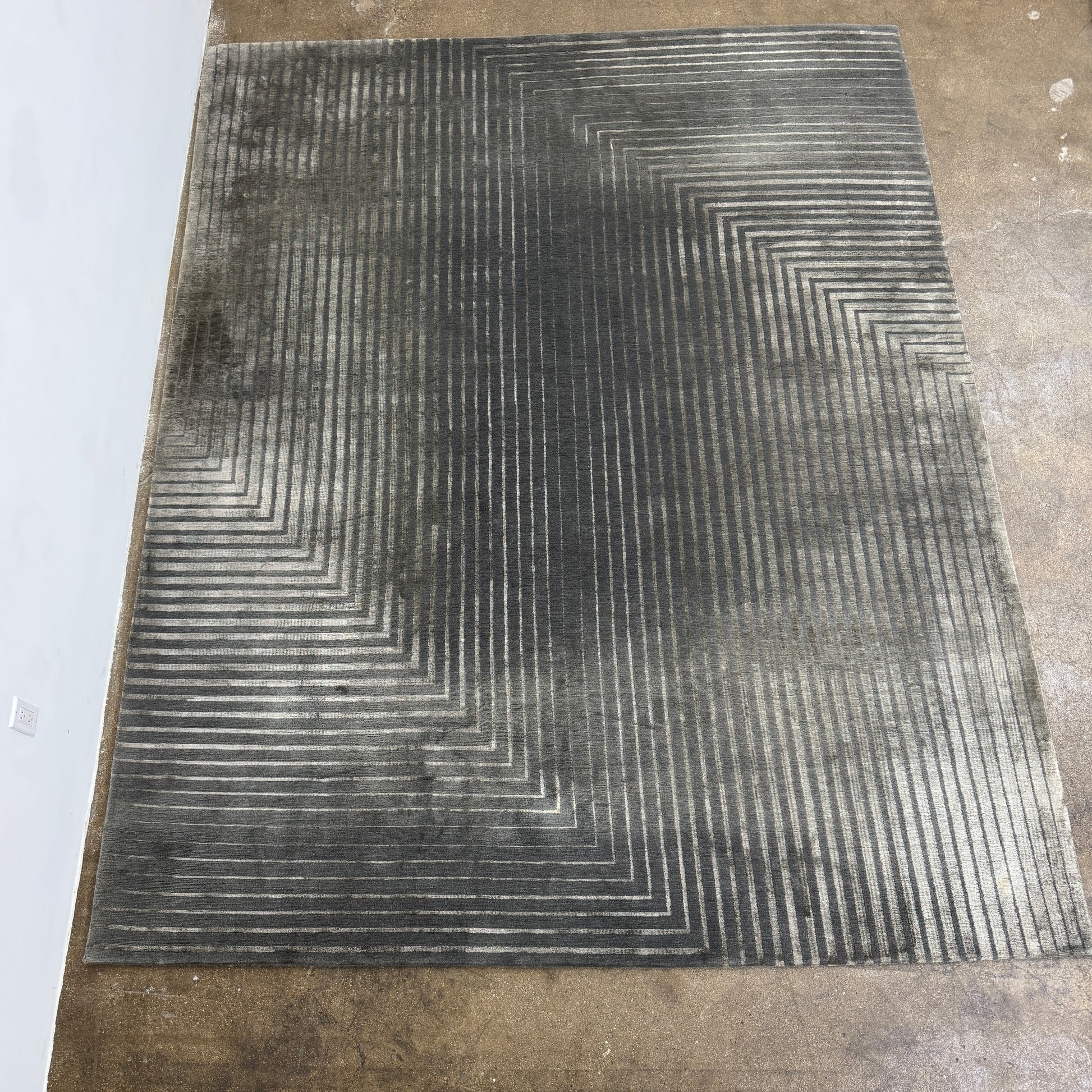 The Delinear Detour Rug 8 x 10 by Delinear features a contemporary rectangular design with a gradient gray pattern and angular geometric lines arranged in a stepped motif.