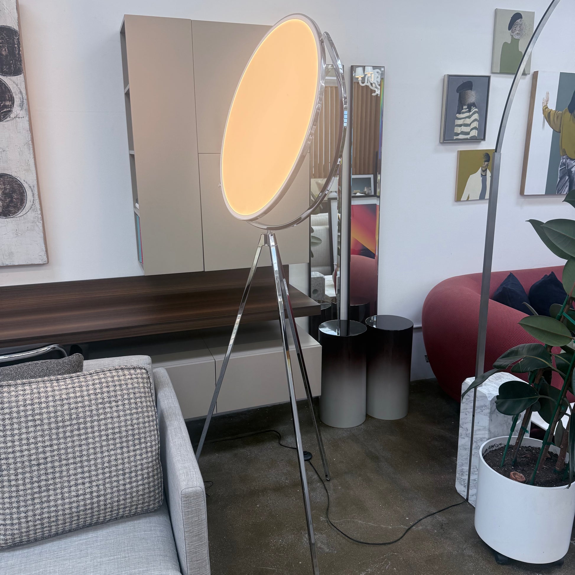 The Flos Superloon Floor Lamp by Flos features a round light on a three-legged chrome stand with a modern tripod design, set against a plain light background.