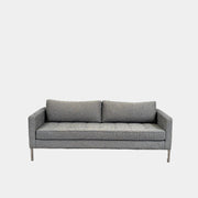 The Blu Dot Paramont Sofa is a grey, three-seater sofa by Blu Dot, featuring metal legs and two back cushions, shown against a plain white background.