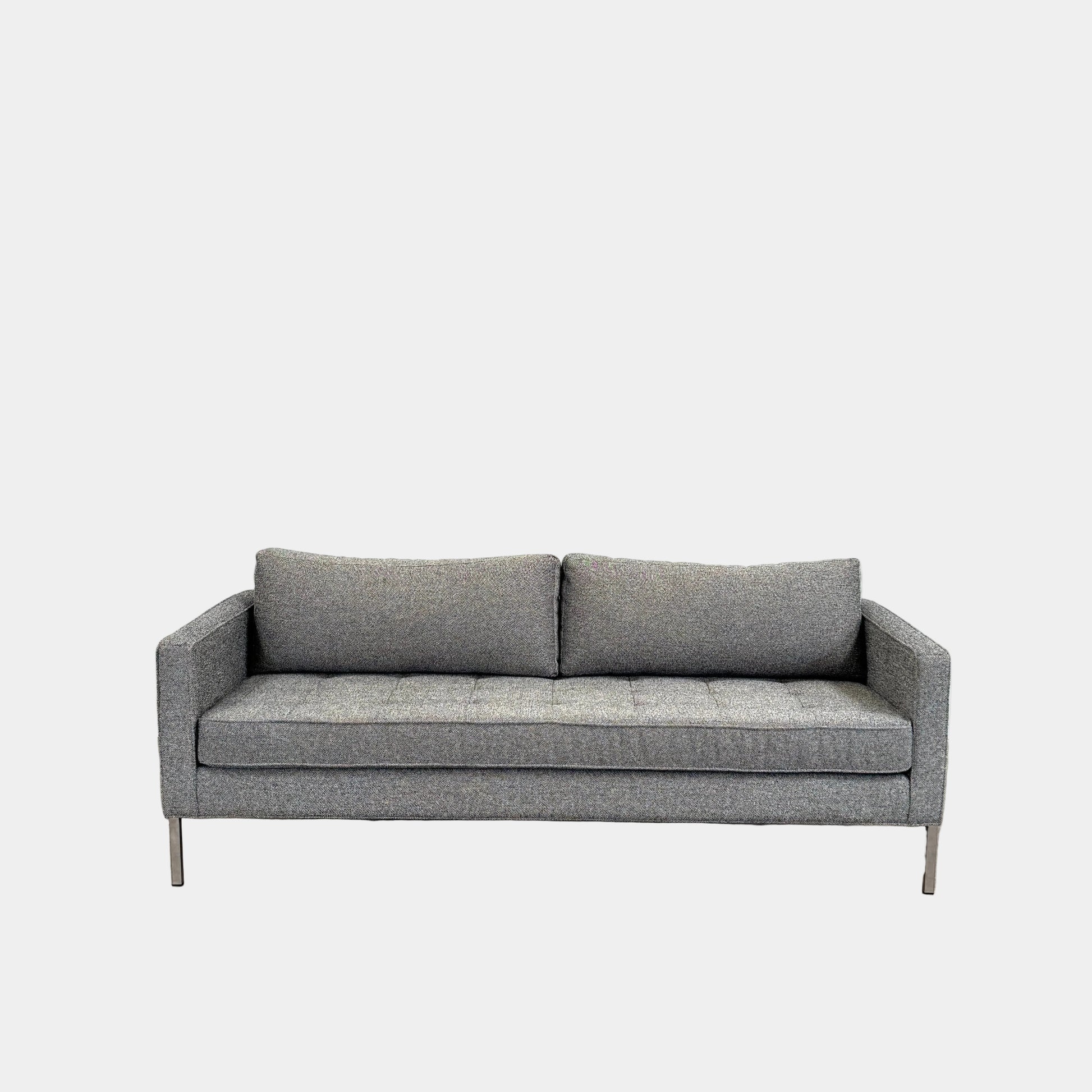 The Blu Dot Paramont Sofa is a grey, three-seater sofa by Blu Dot, featuring metal legs and two back cushions, shown against a plain white background.