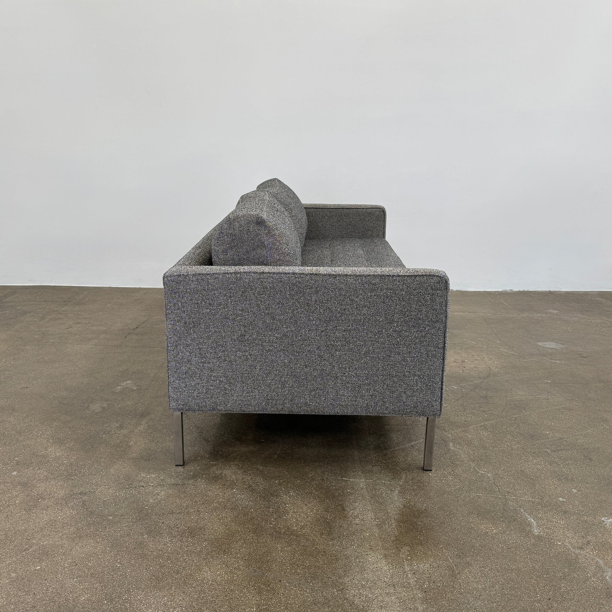 The Blu Dot Paramont Sofa is a grey, three-seater sofa by Blu Dot, featuring metal legs and two back cushions, shown against a plain white background.