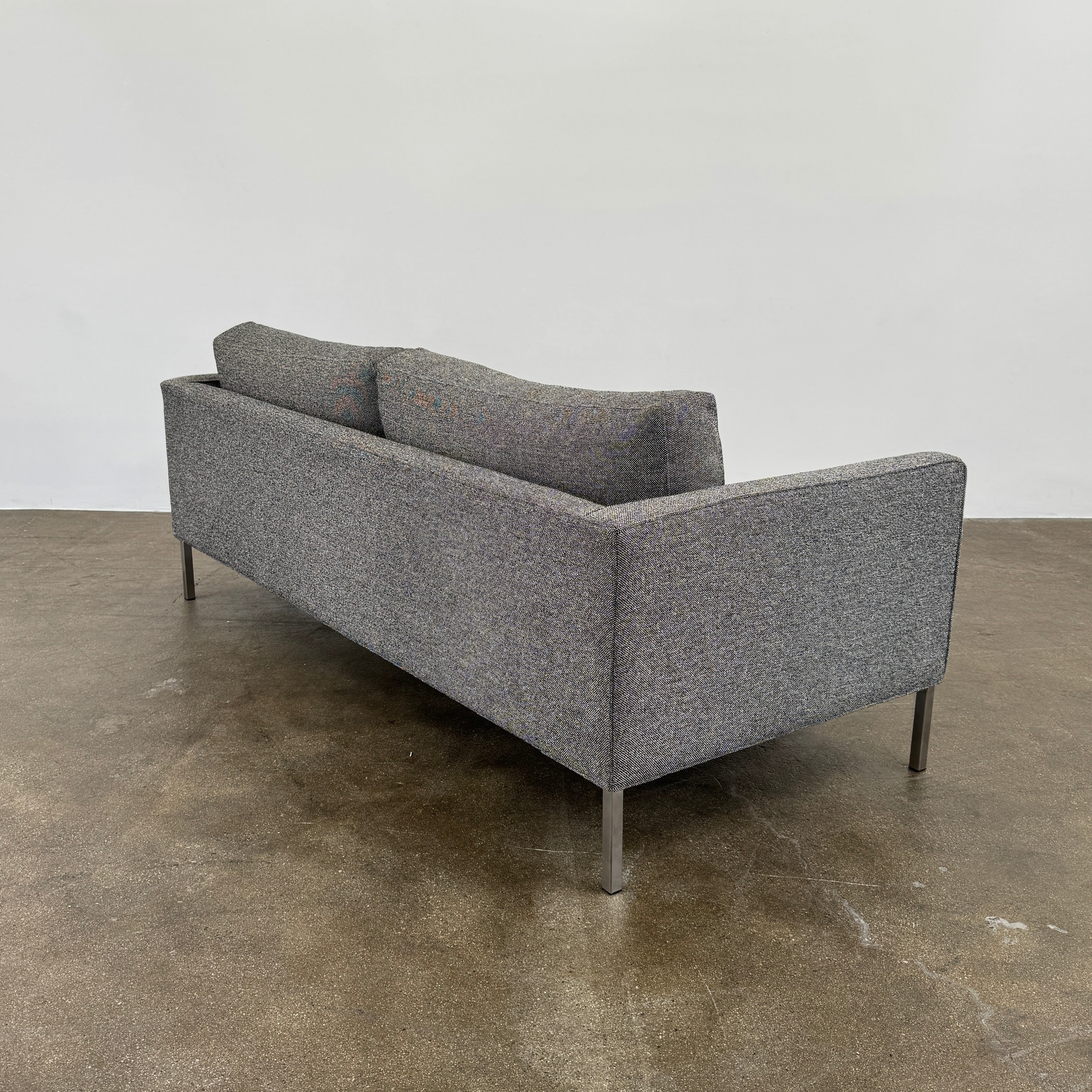 The Blu Dot Paramont Sofa is a grey, three-seater sofa by Blu Dot, featuring metal legs and two back cushions, shown against a plain white background.