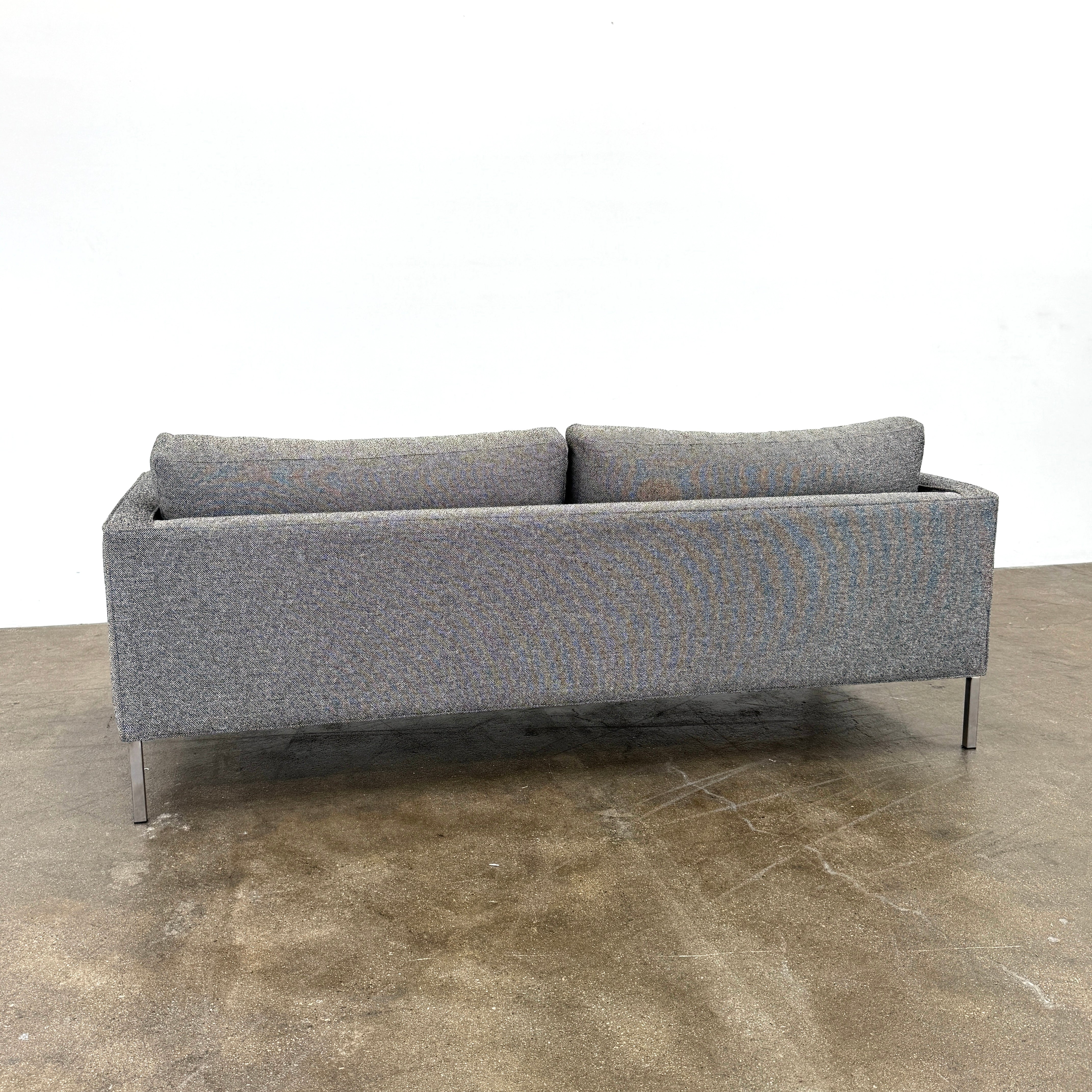The Blu Dot Paramont Sofa is a grey, three-seater sofa by Blu Dot, featuring metal legs and two back cushions, shown against a plain white background.