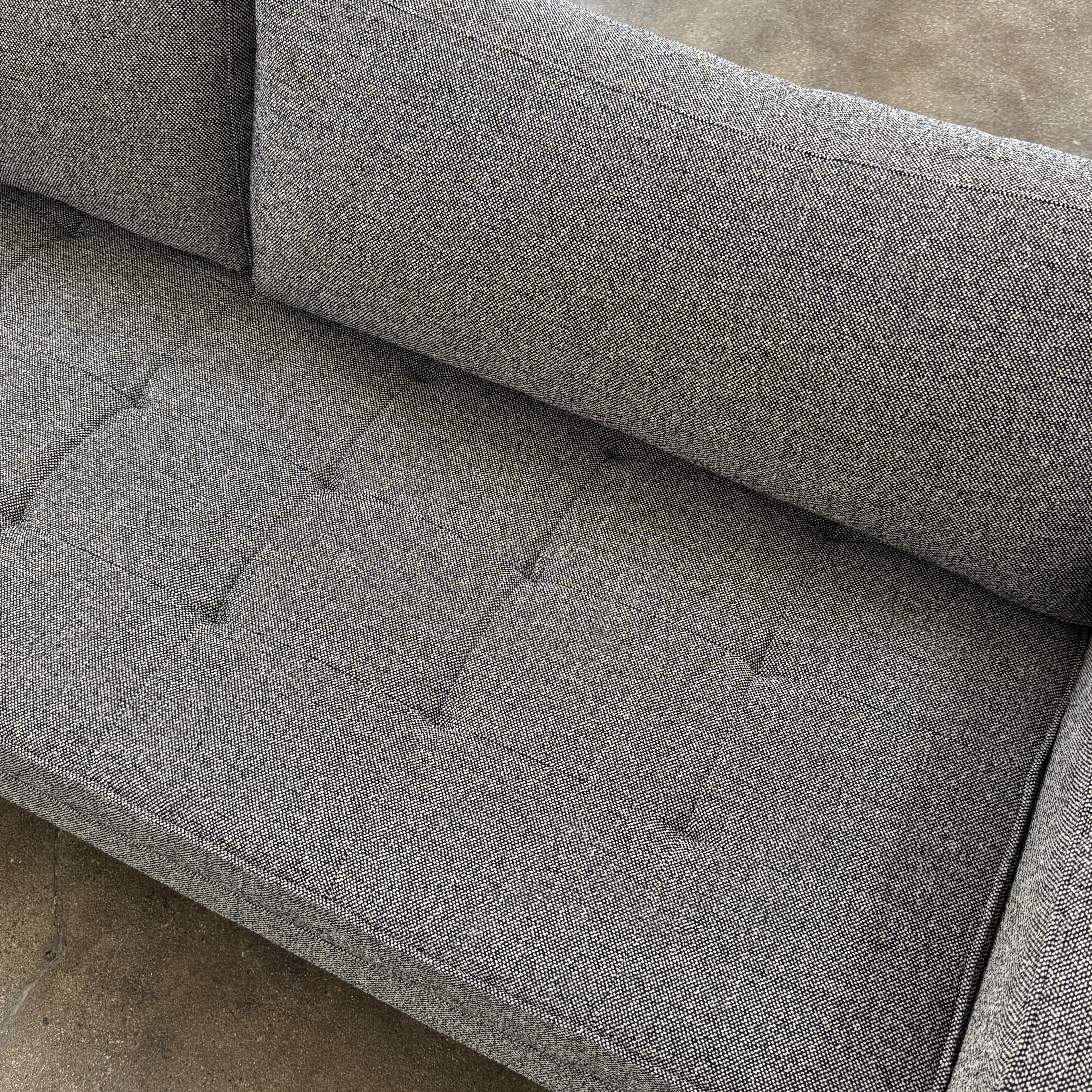 The Blu Dot Paramont Sofa is a grey, three-seater sofa by Blu Dot, featuring metal legs and two back cushions, shown against a plain white background.