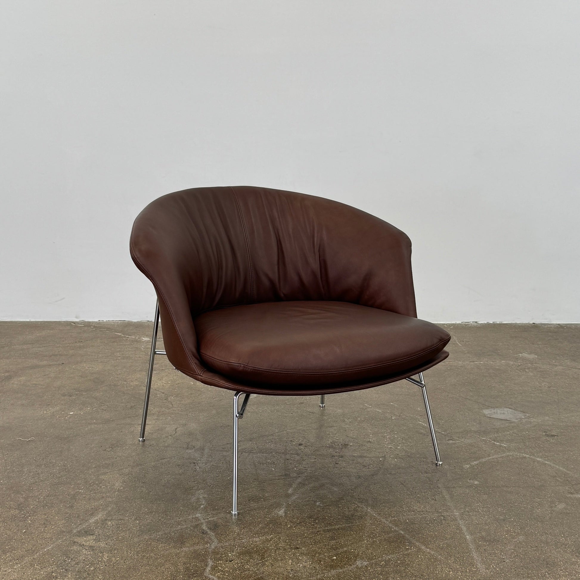 The Driade Moon Lounge Chair by Driade features a modern brown leather design, curved backrest, and slim metal legs, shown against a plain white background.