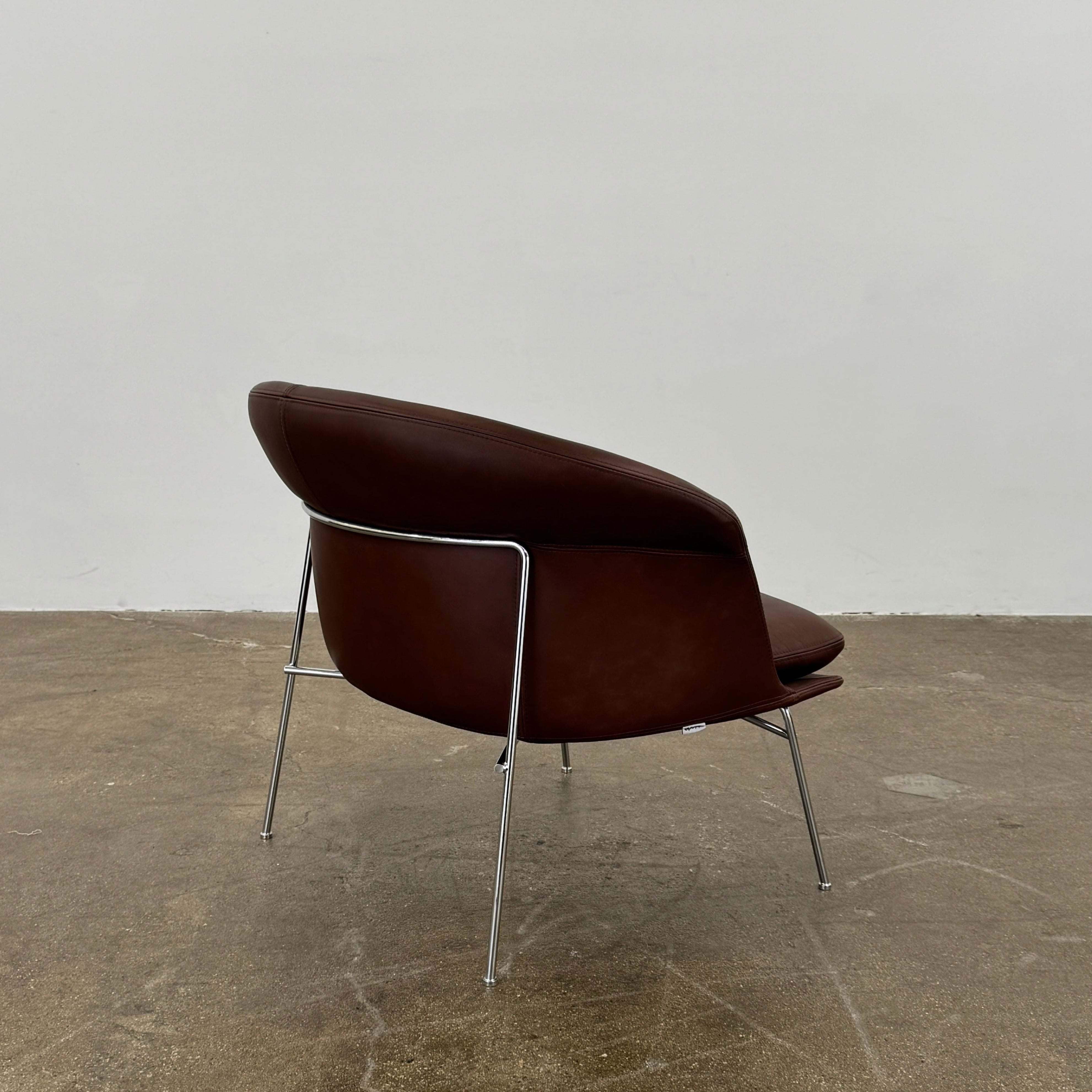 The Driade Moon Lounge Chair by Driade features a modern brown leather design, curved backrest, and slim metal legs, shown against a plain white background.